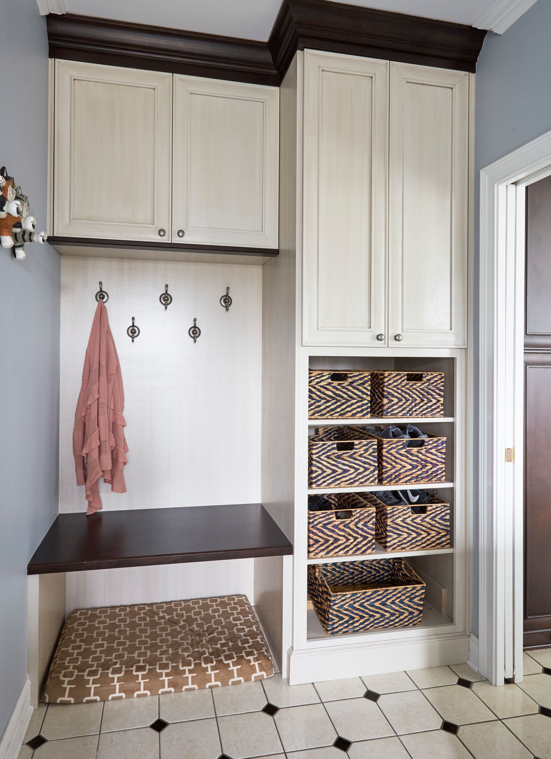 A room with white cabinets and baskets on shelves