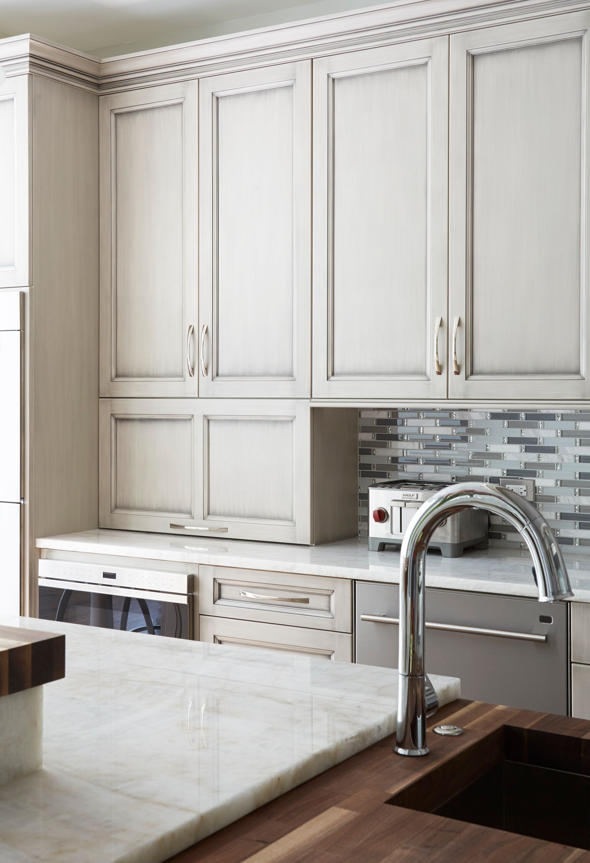 A kitchen with white cabinets , a sink , and a toaster oven.