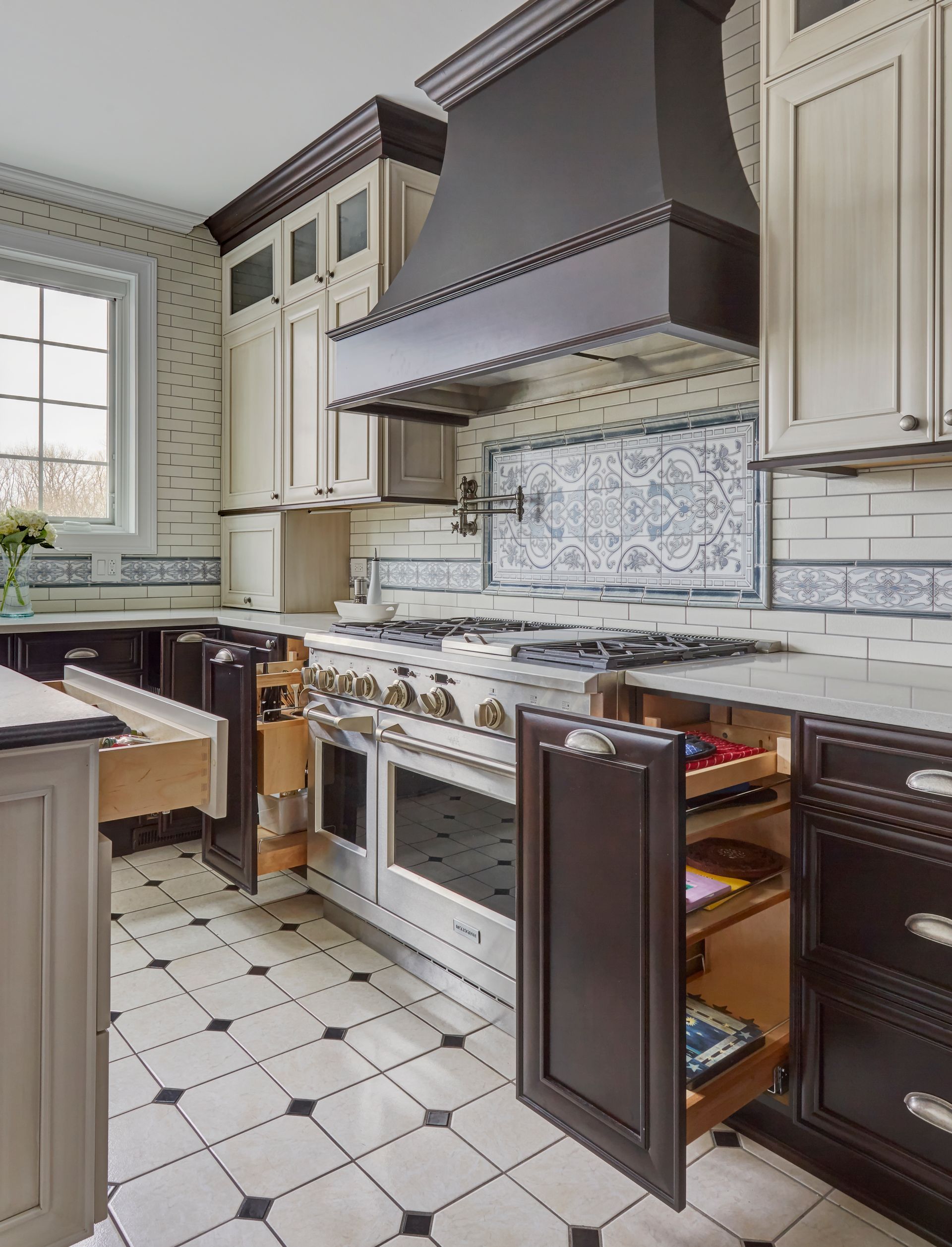 A kitchen with stainless steel appliances and black and white tile floors.
