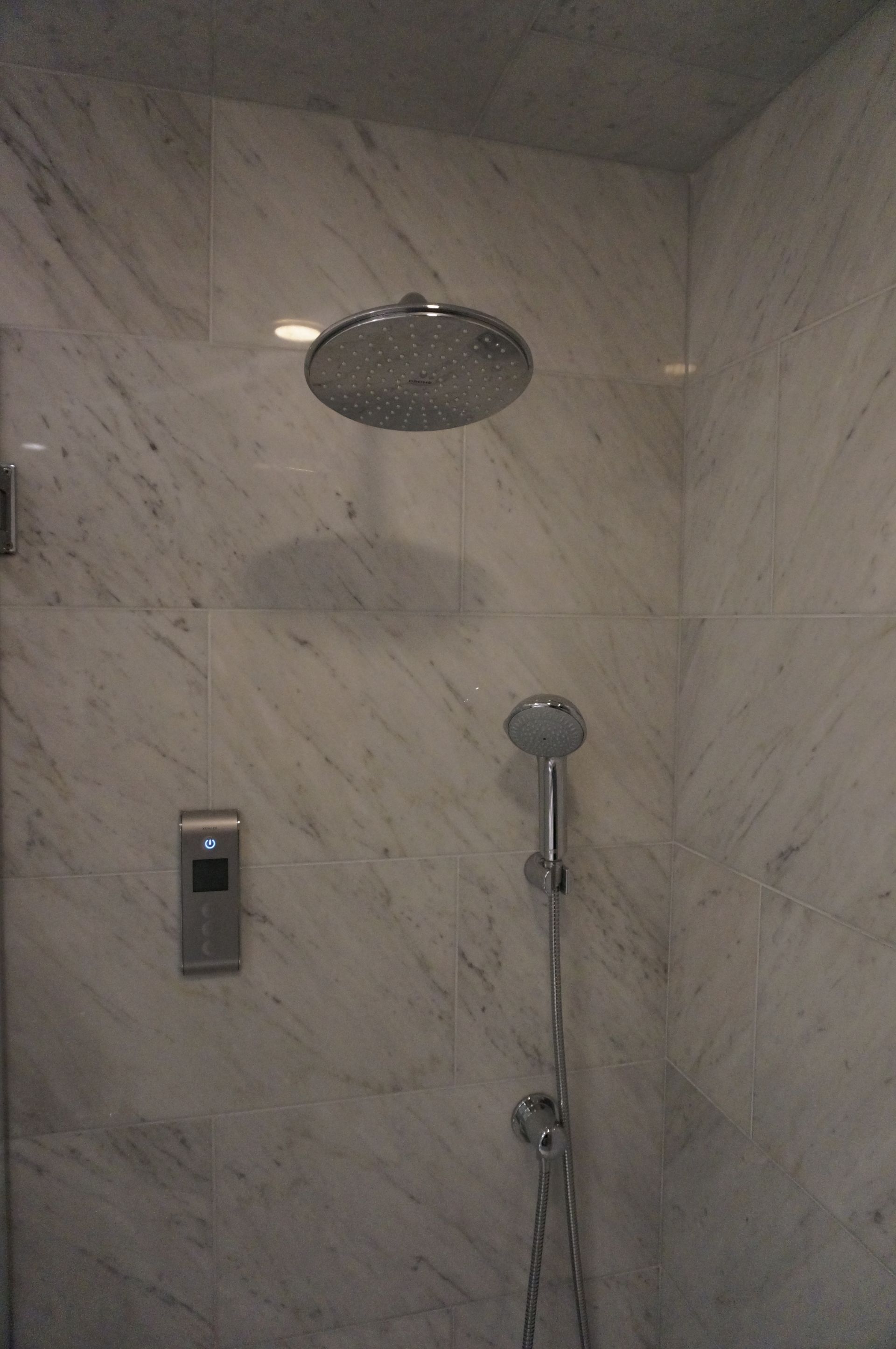 A shower head is hanging from the ceiling in a bathroom.