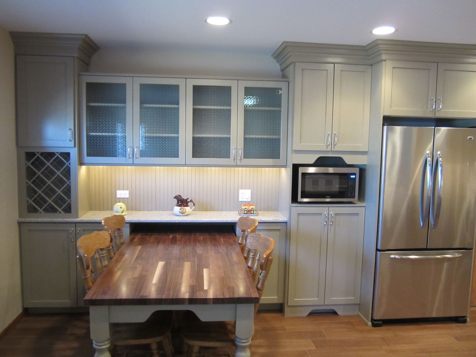 A kitchen with a table , chairs , refrigerator and microwave.