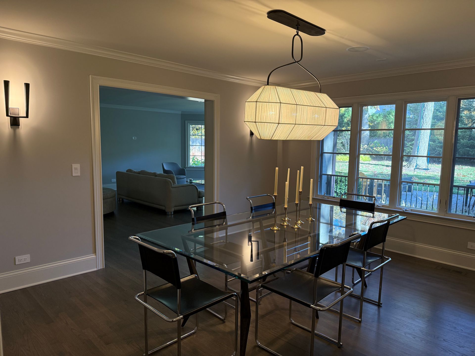 A dining room with a glass table and chairs and a chandelier hanging from the ceiling.