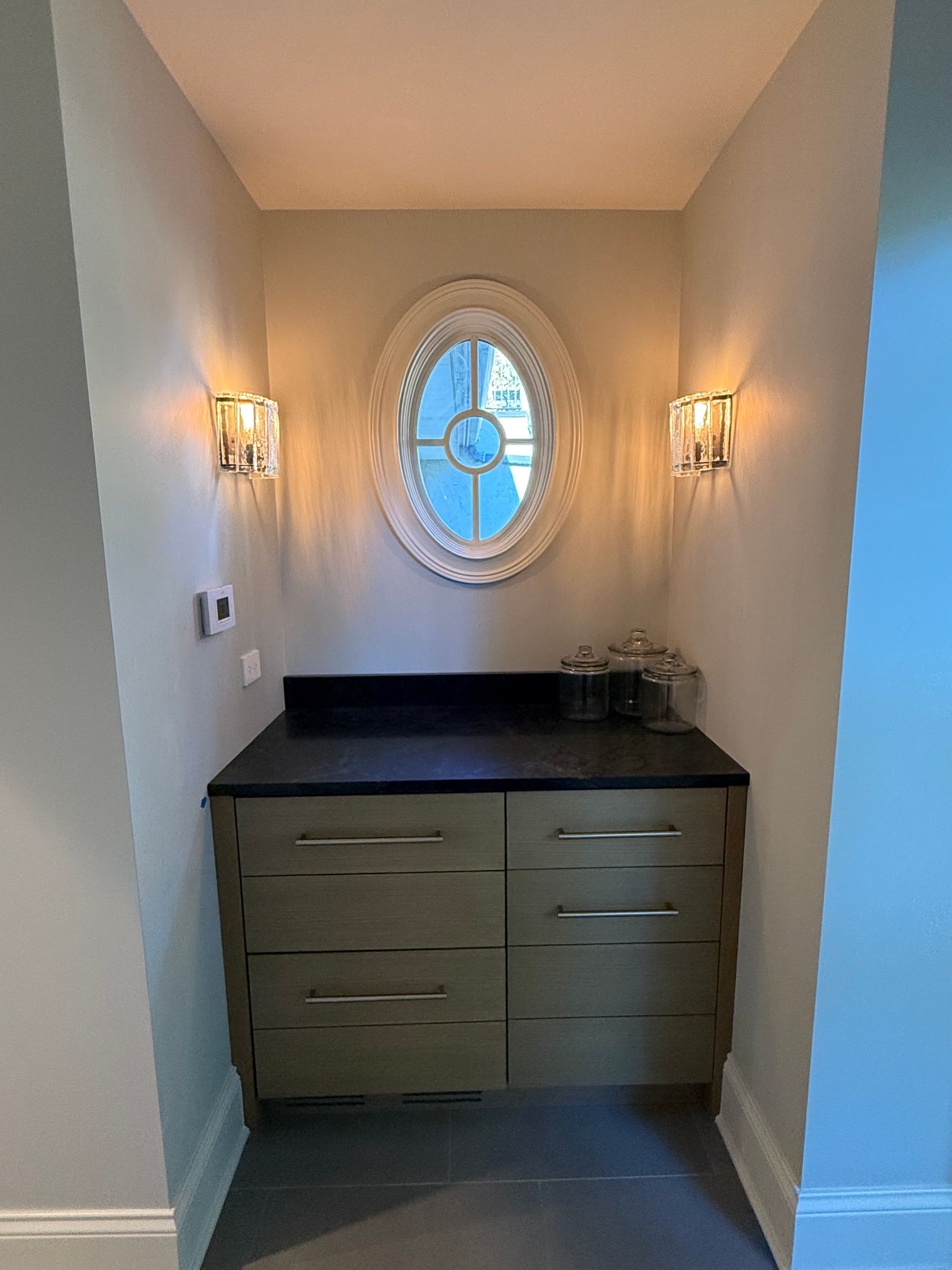 A small room with a dresser and a round window.