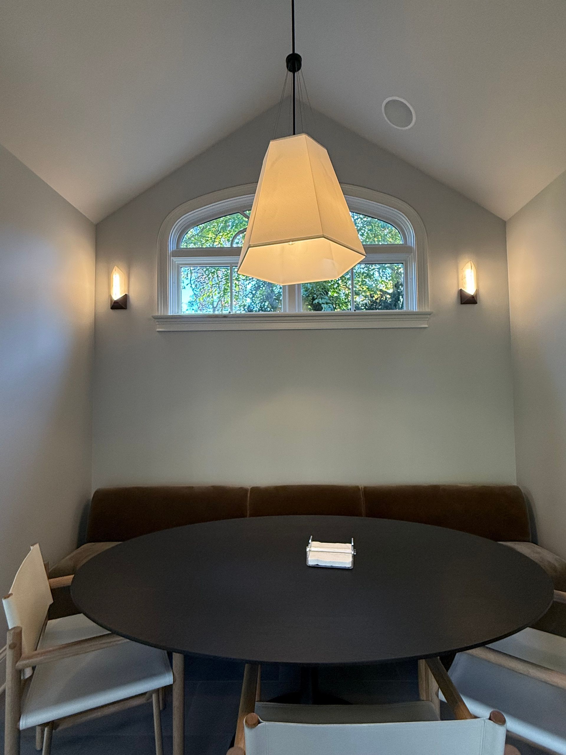 A dining room with a round table and chairs and a window