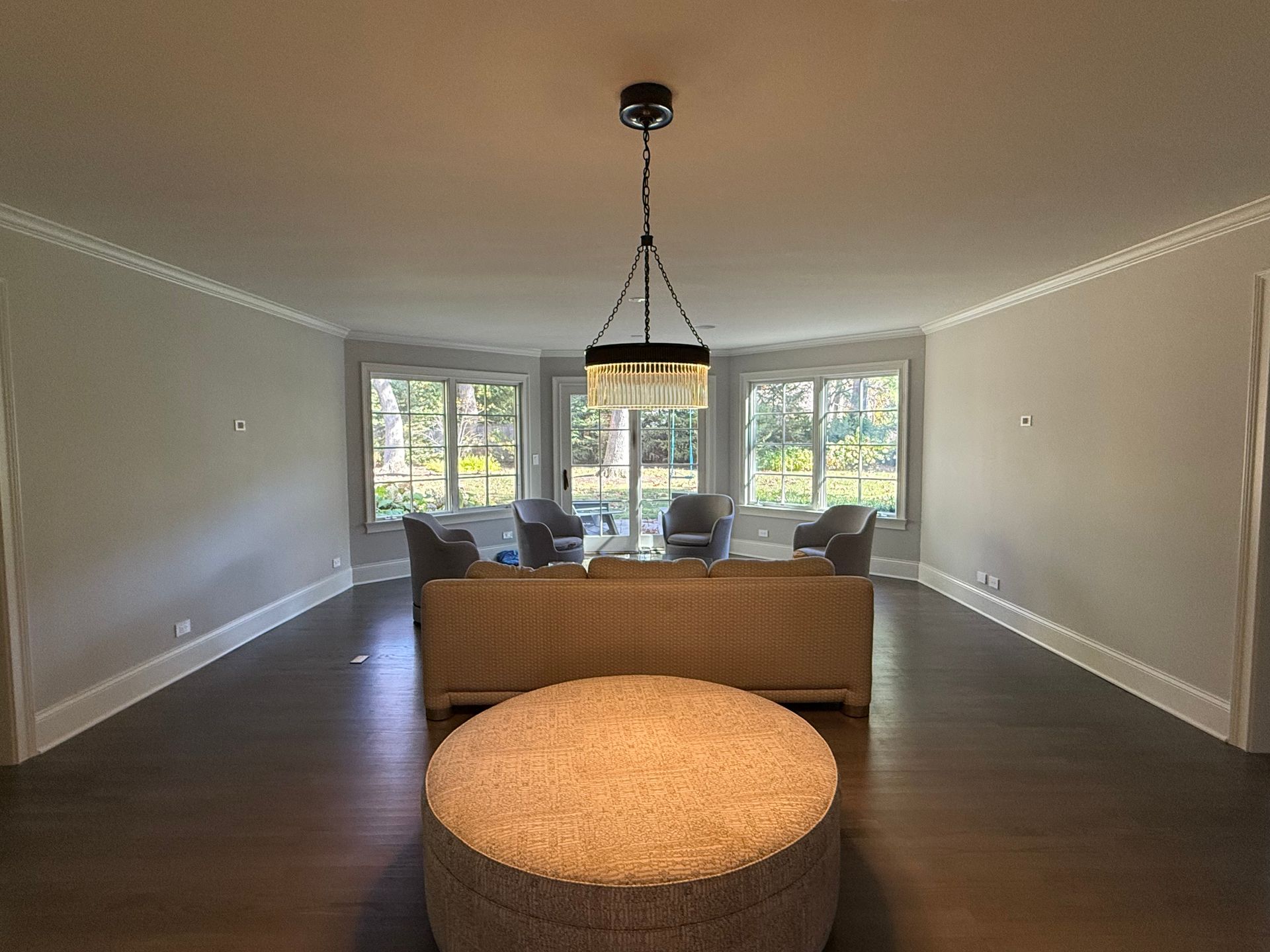 A living room with a couch , chairs , ottoman and a chandelier.