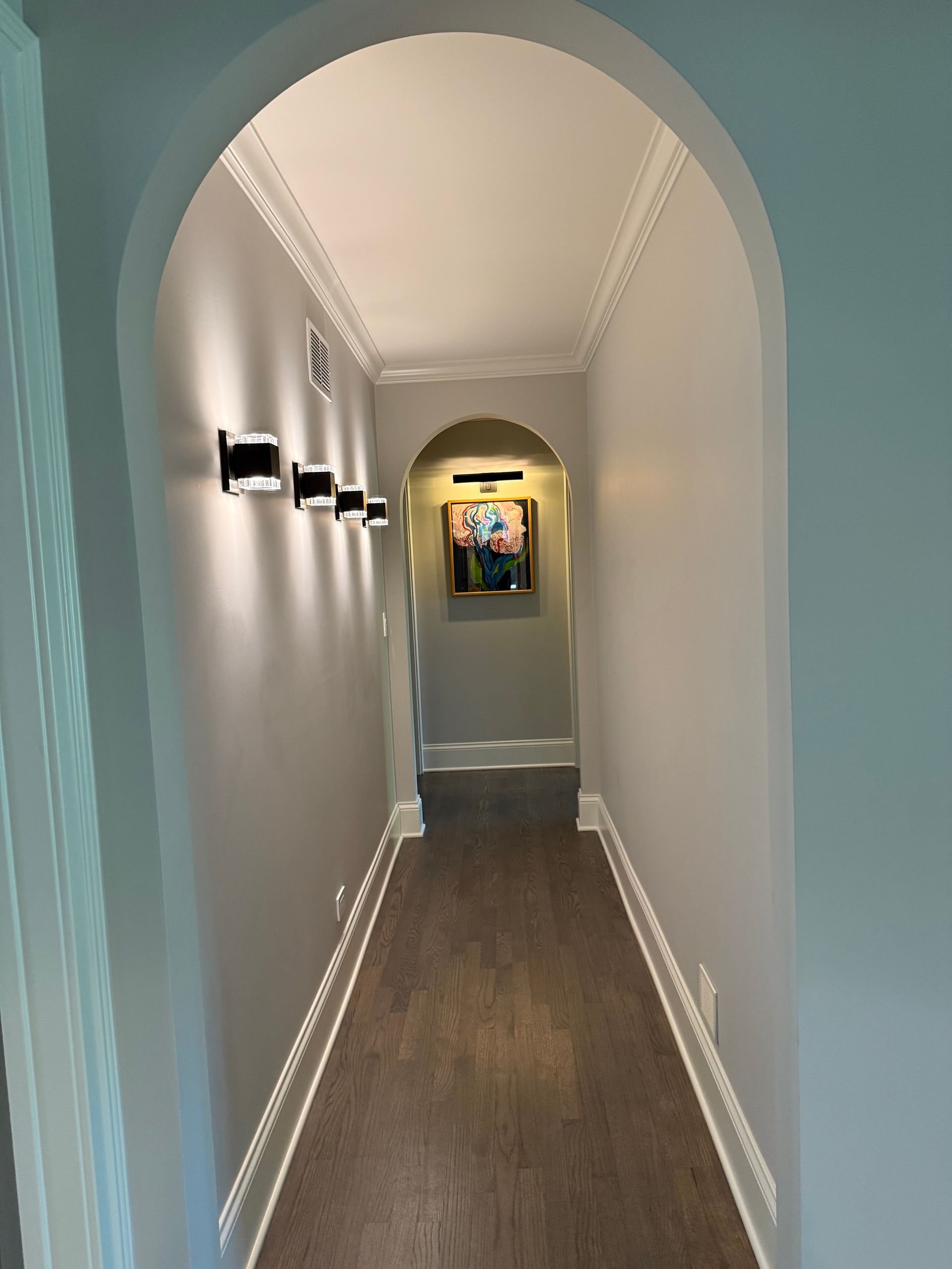 A long hallway with a picture on the wall and lights on the walls.