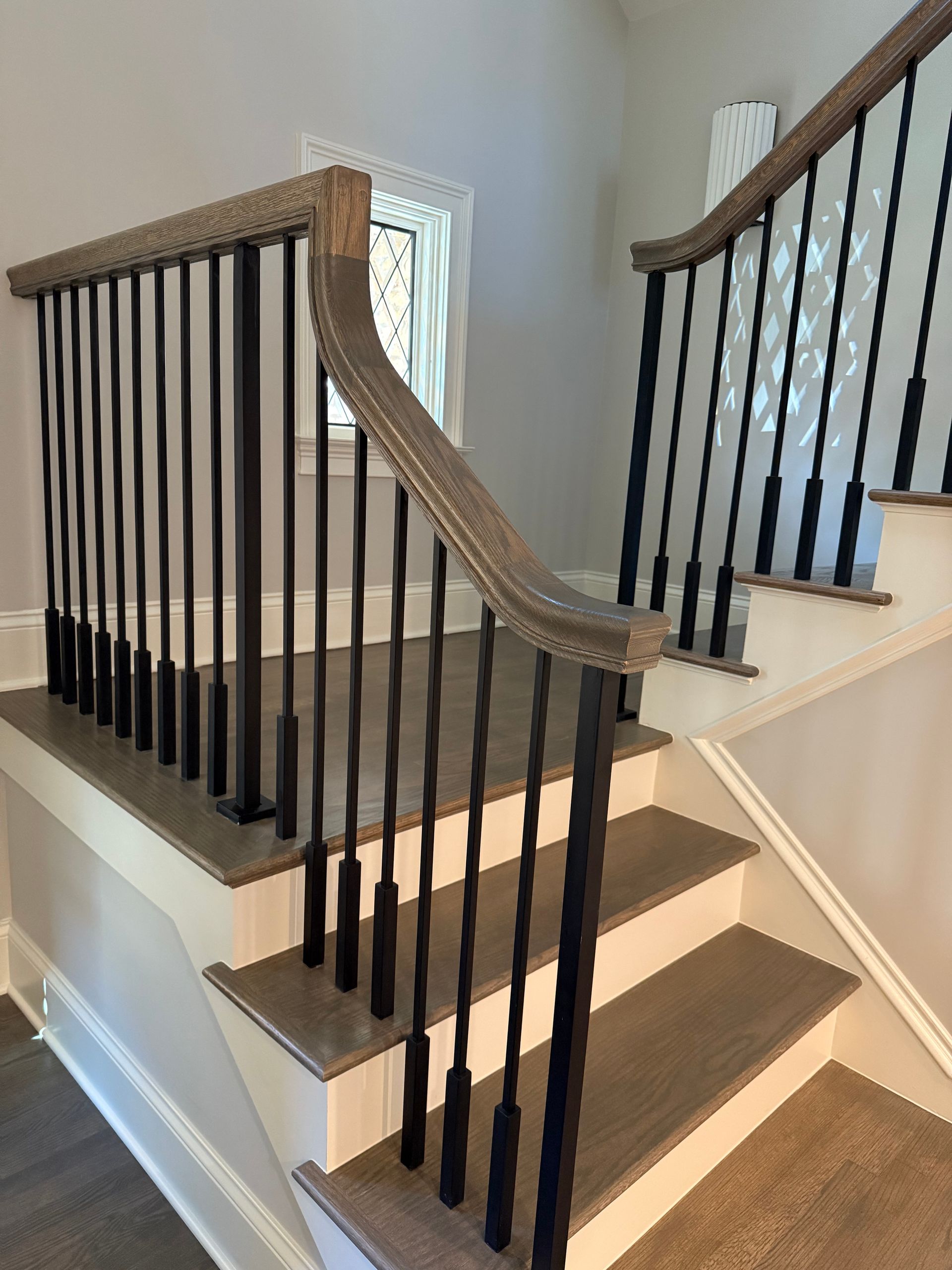 A staircase with a black railing and a wooden handrail.
