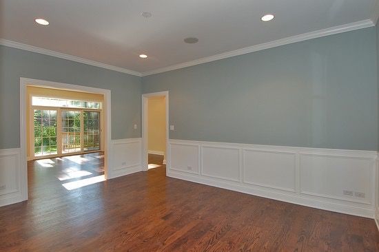 An empty living room with hardwood floors and blue walls.