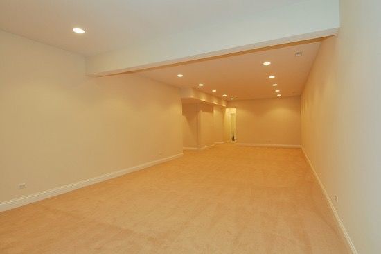 An empty room with white walls and a tan carpet.