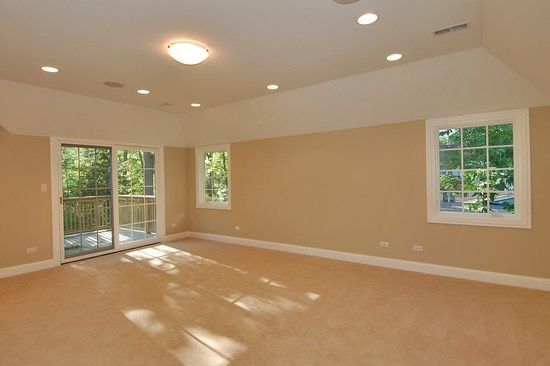 An empty room with two windows and a sliding glass door.