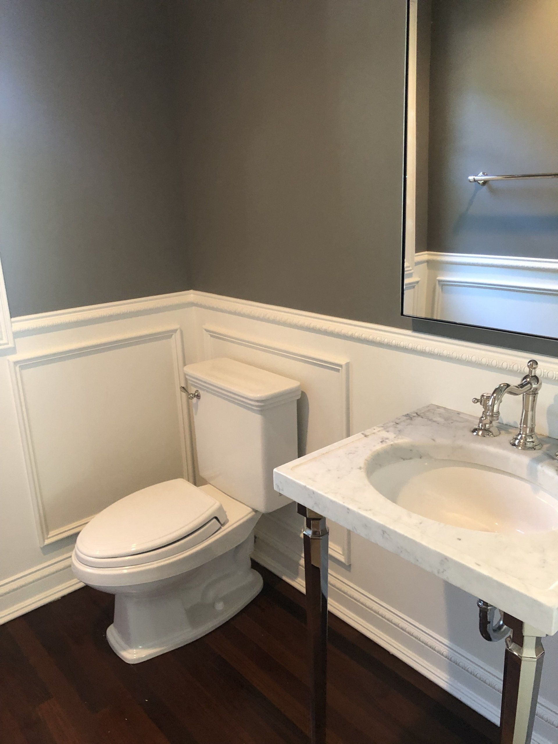 A bathroom with a toilet , sink and mirror.