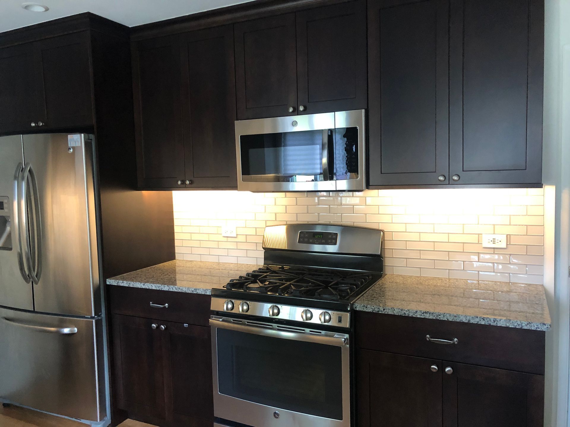 A kitchen with stainless steel appliances and dark cabinets