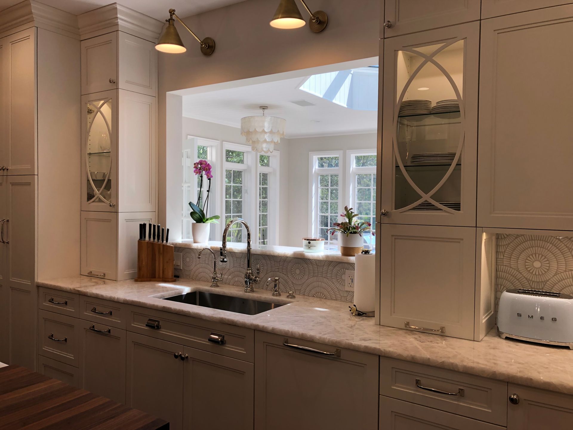 A kitchen with white cabinets , a sink , and a toaster oven.