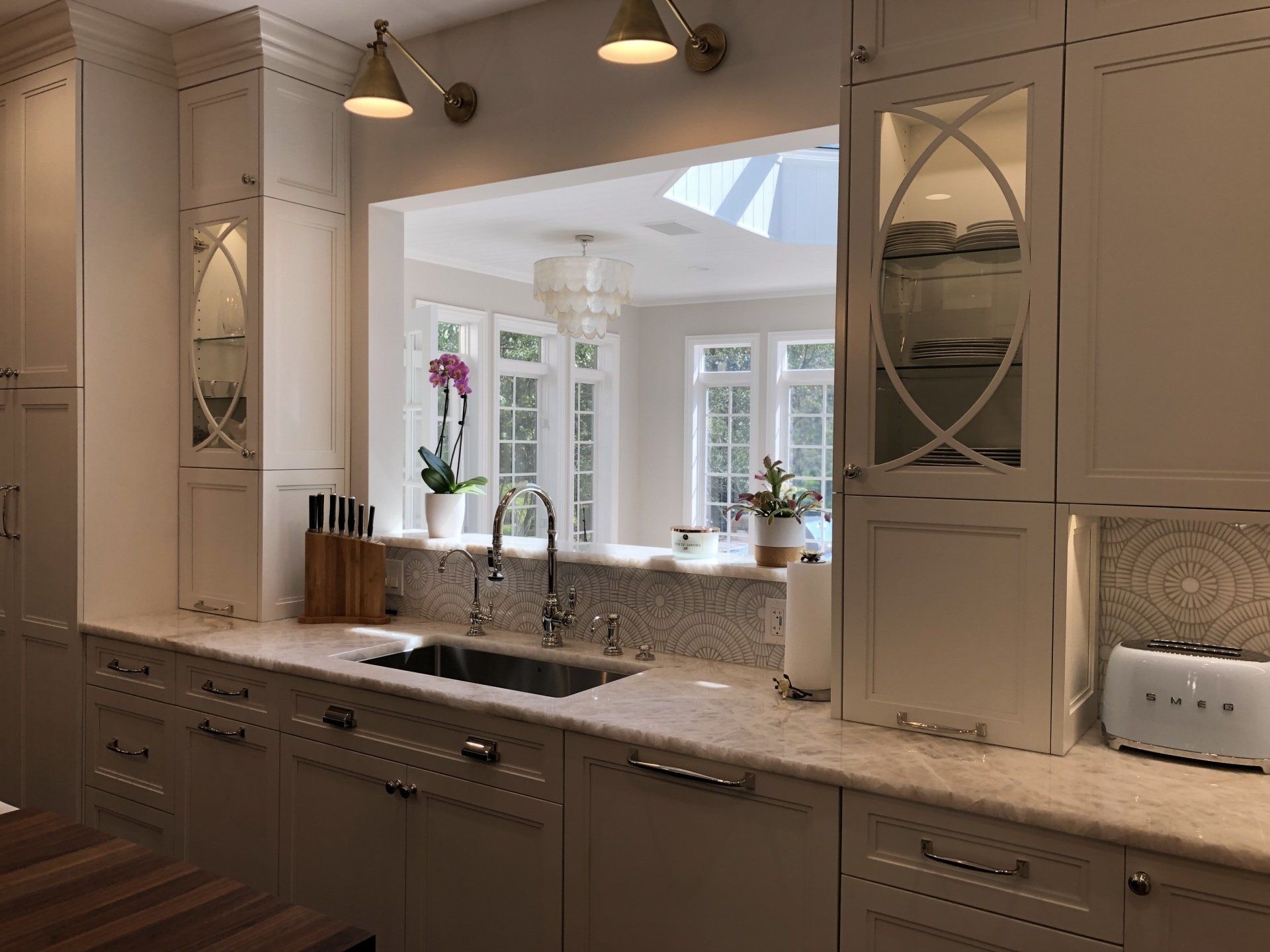 A kitchen with white cabinets , a sink , and a window.