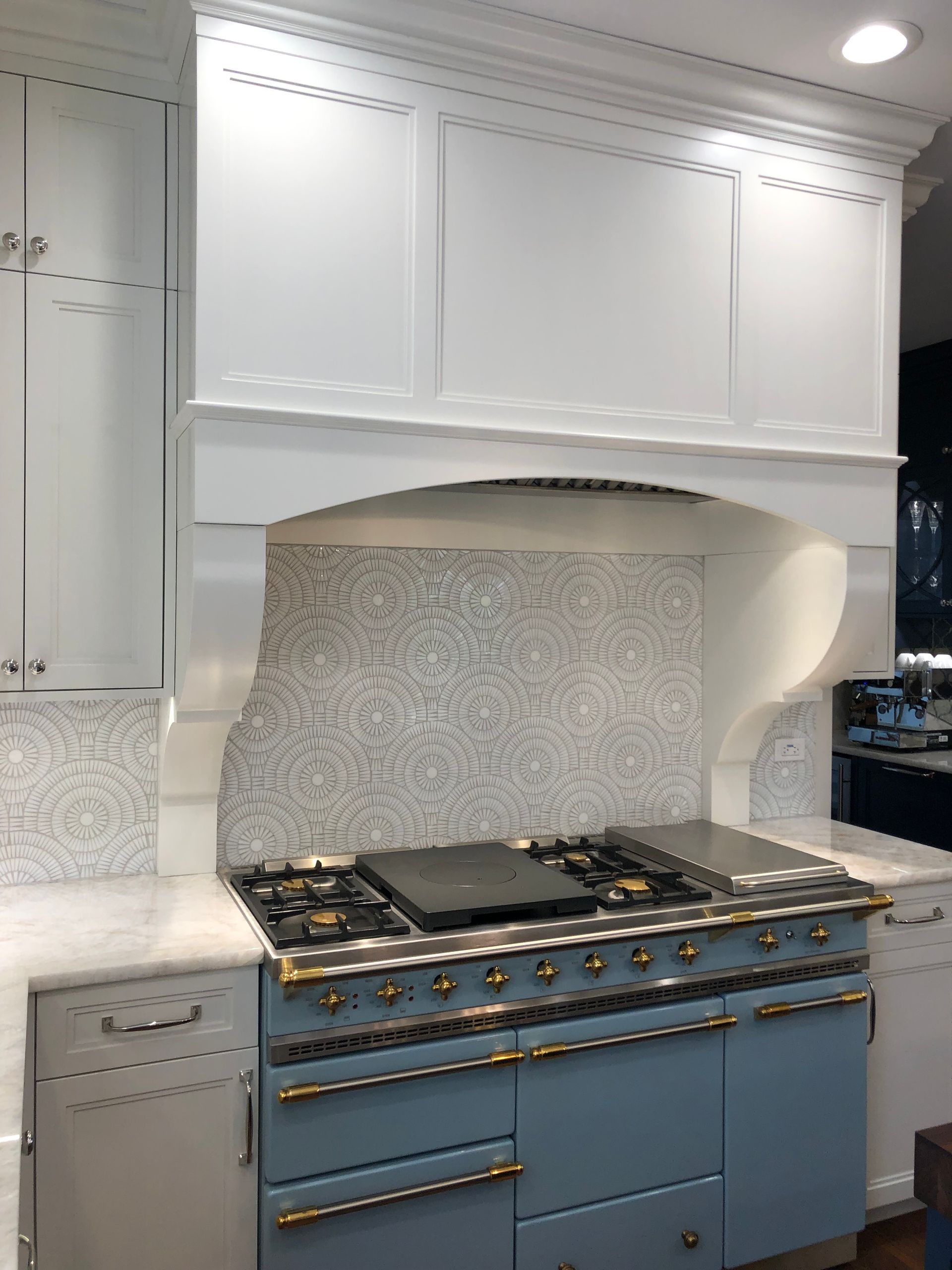 A kitchen with a blue stove top oven and white cabinets.