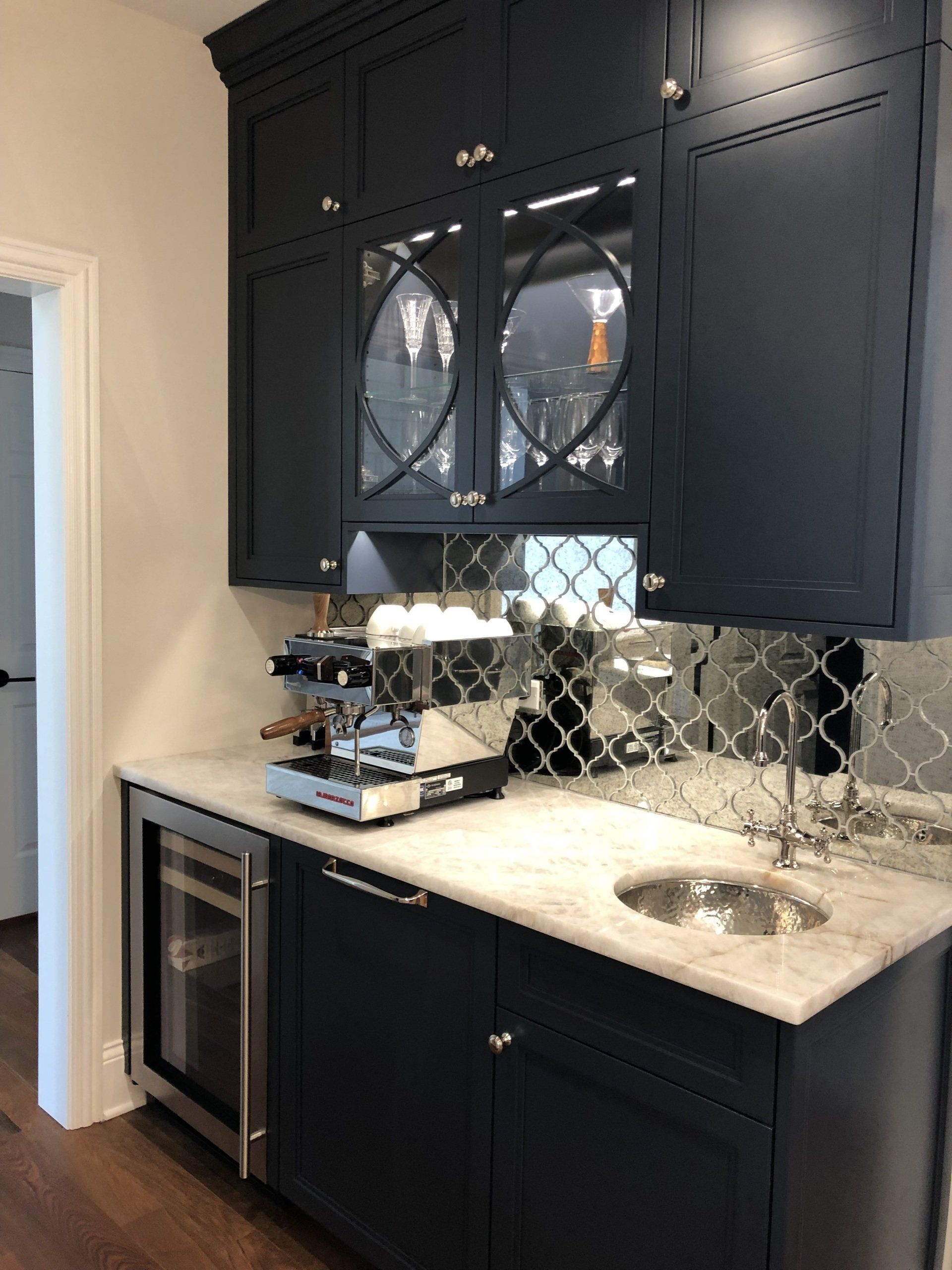 A kitchen with blue cabinets , a sink , and a coffee maker.