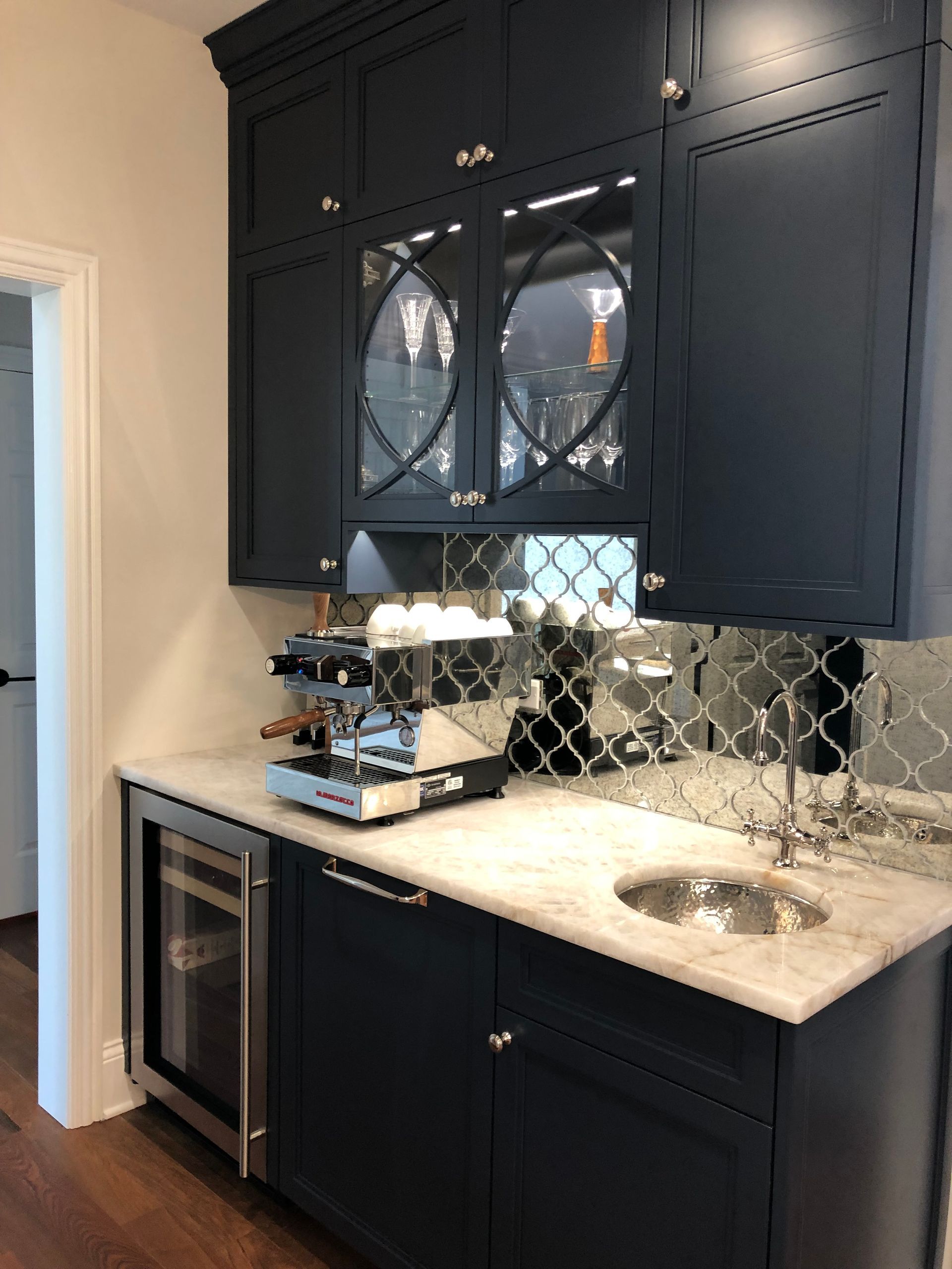 A kitchen with blue cabinets , a sink , and a coffee maker.