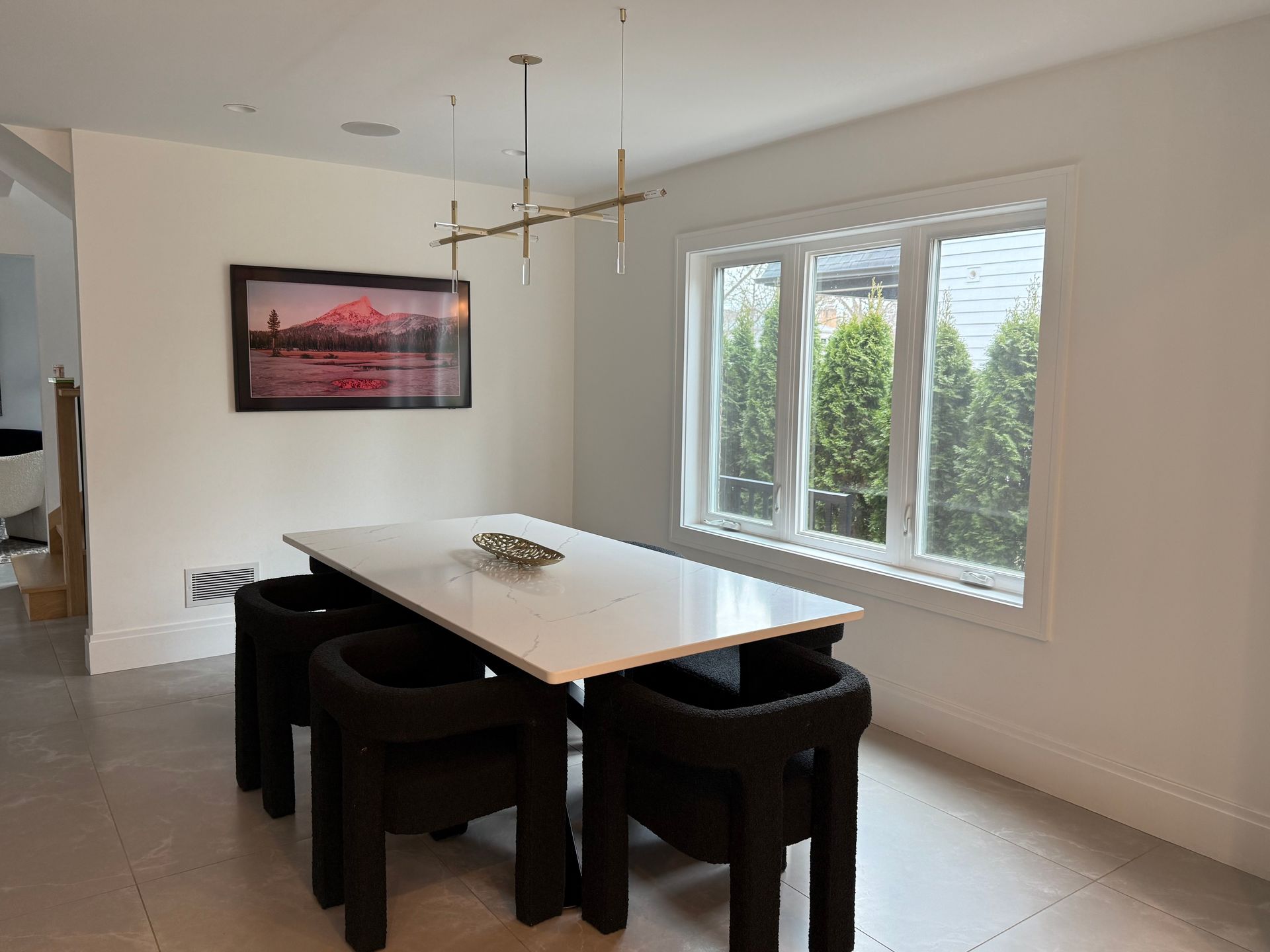 A dining room with a table and chairs and a picture on the wall.
