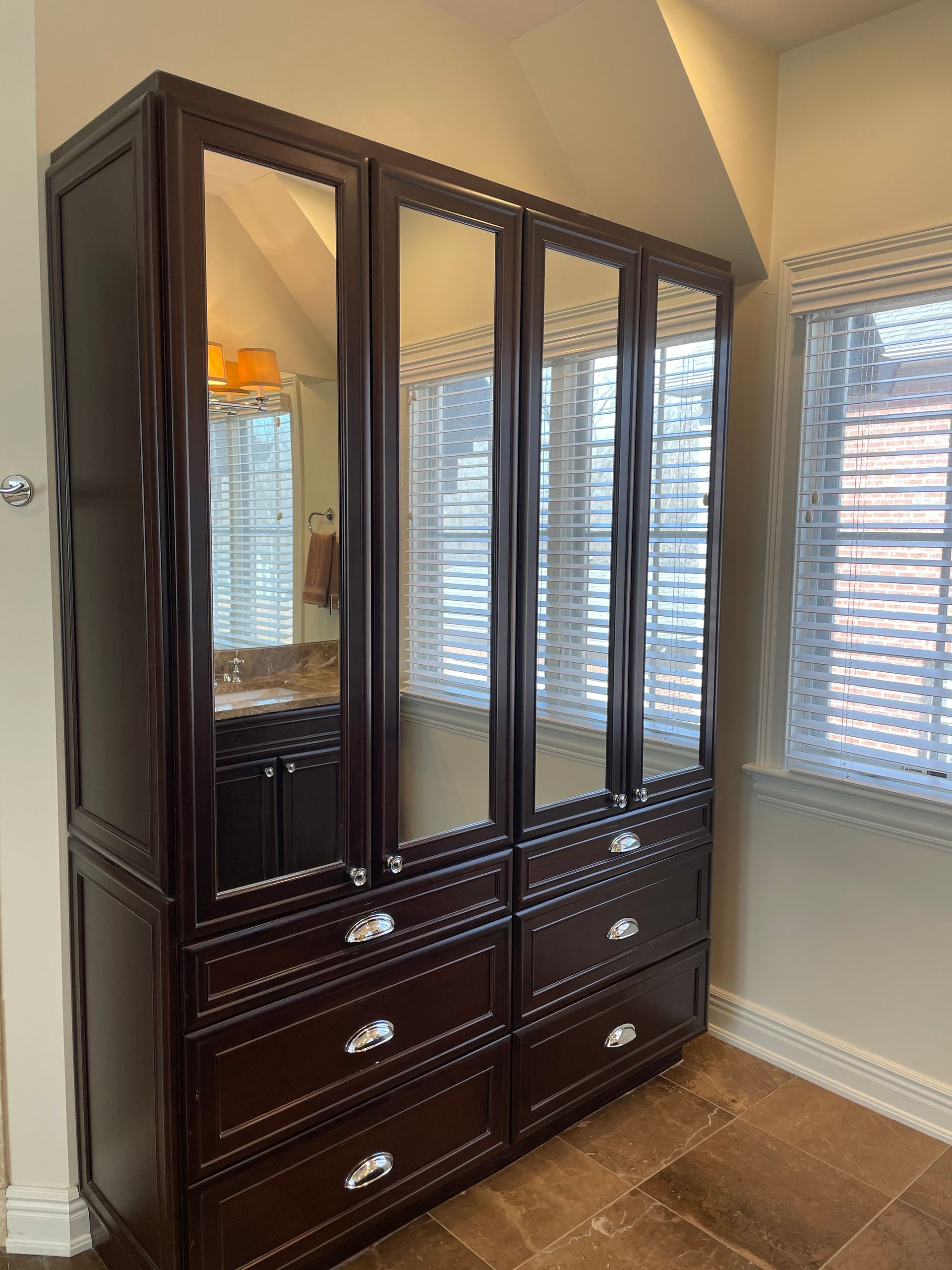 A bathroom with a large cabinet with drawers and mirrors.
