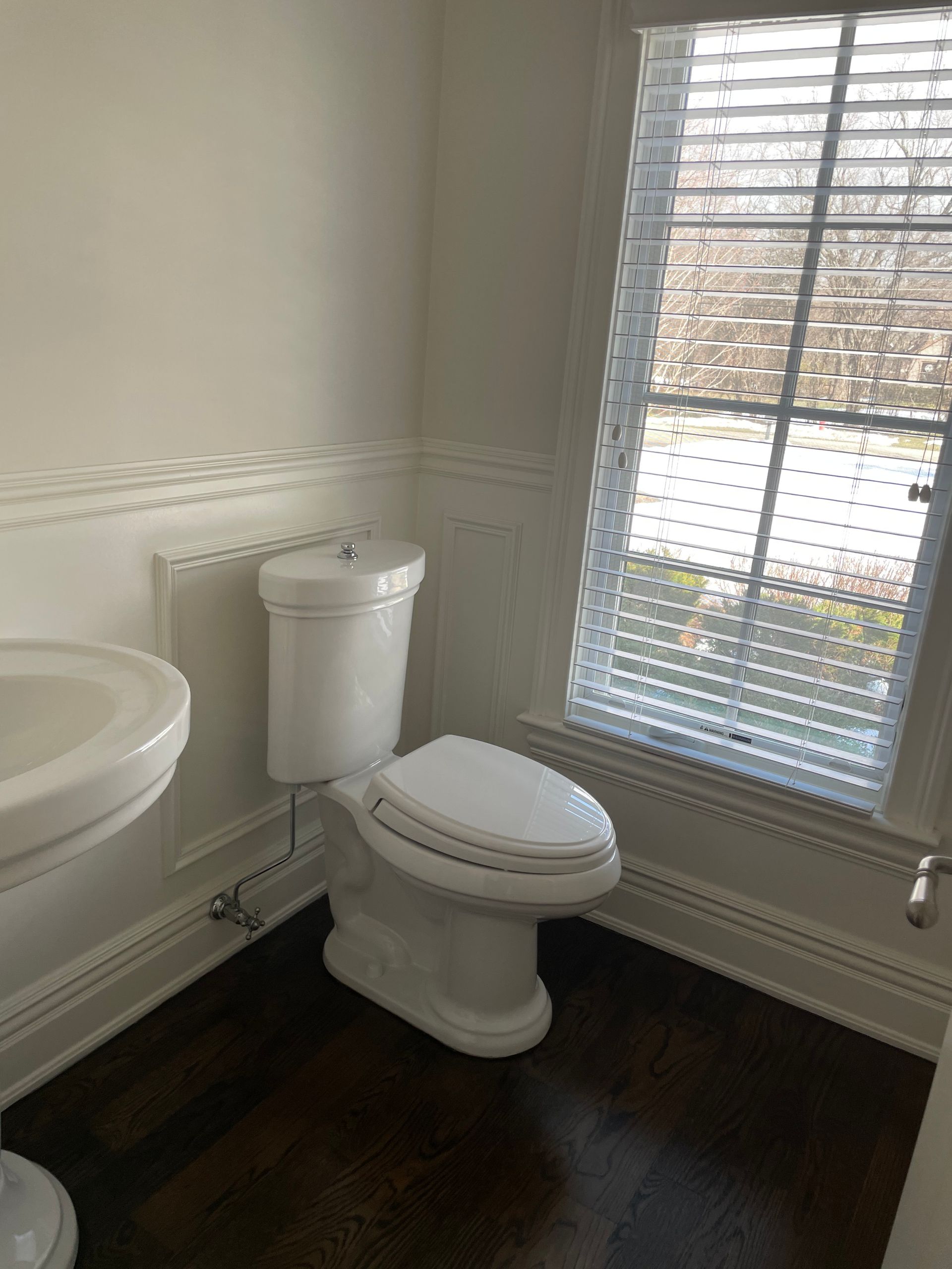 A bathroom with a toilet , sink and window.