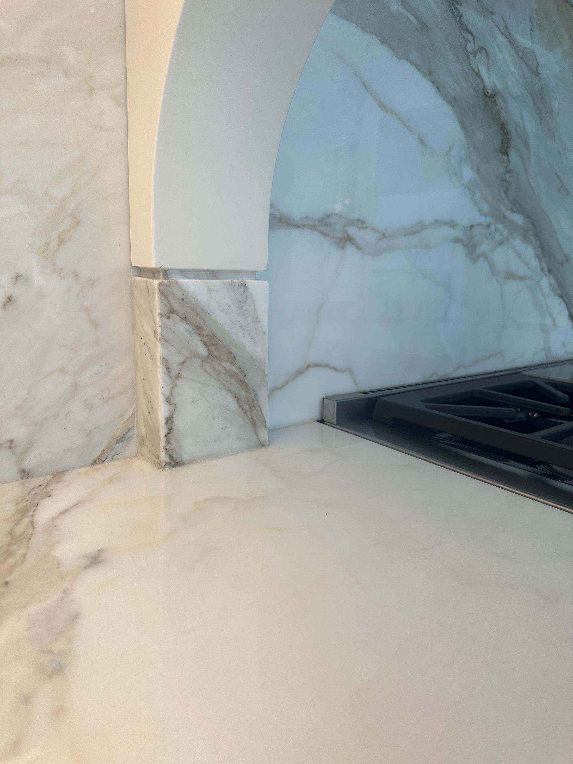 A kitchen with a stove top oven and a marble counter top.