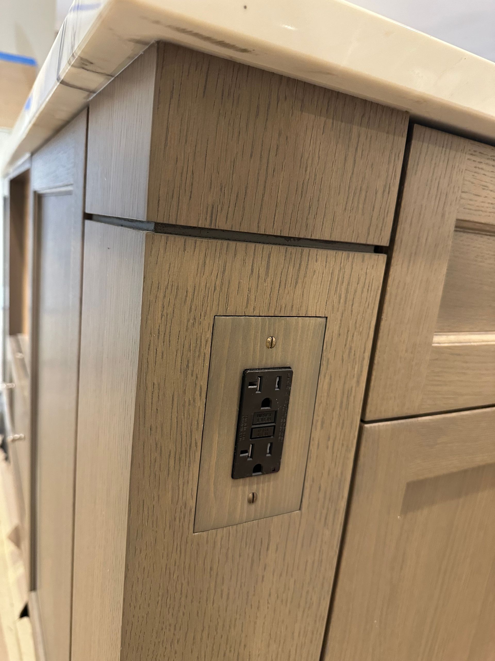 A close up of a electrical outlet on the side of a cabinet.