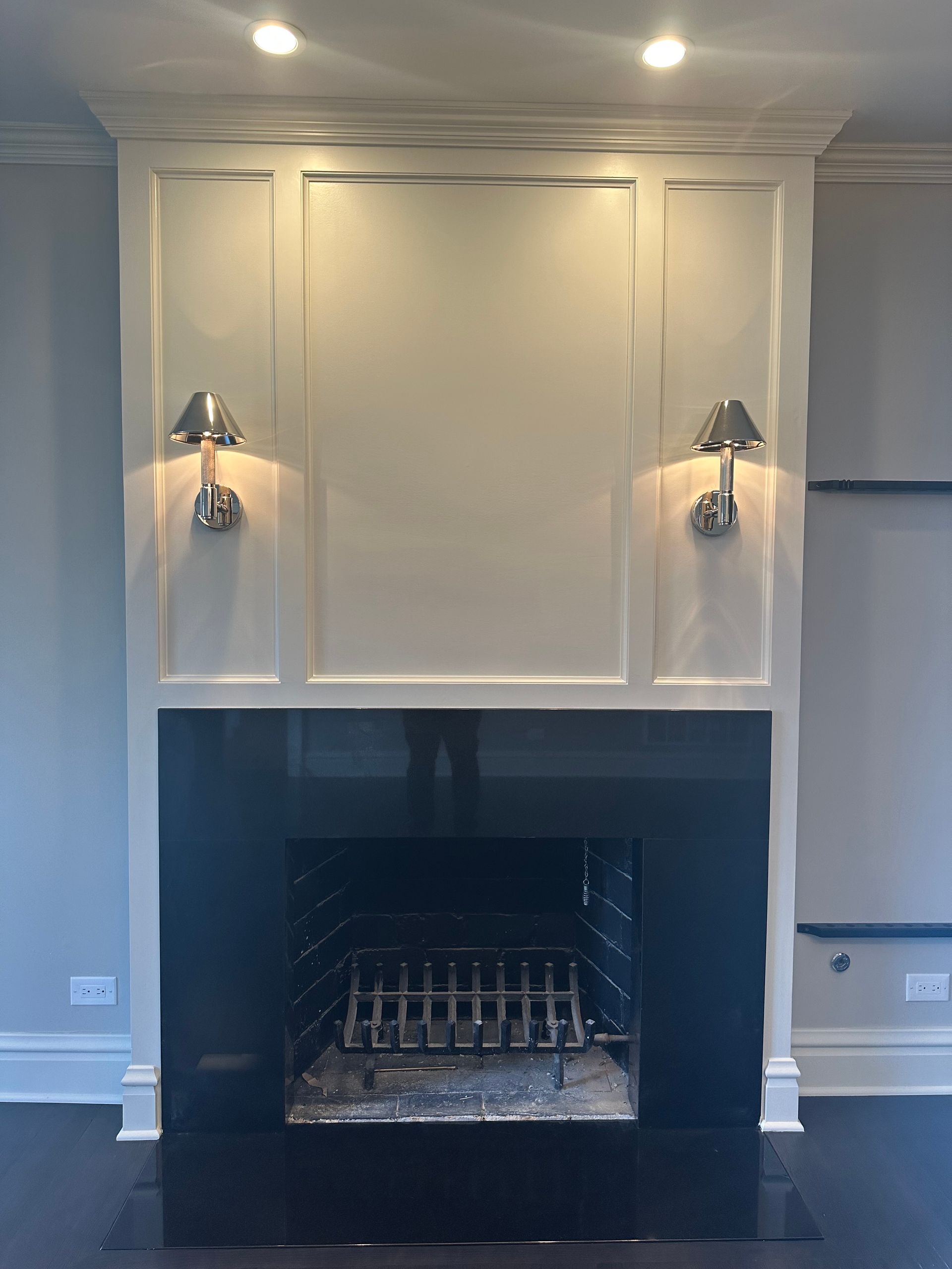 A living room with a fireplace and two lamps on the wall