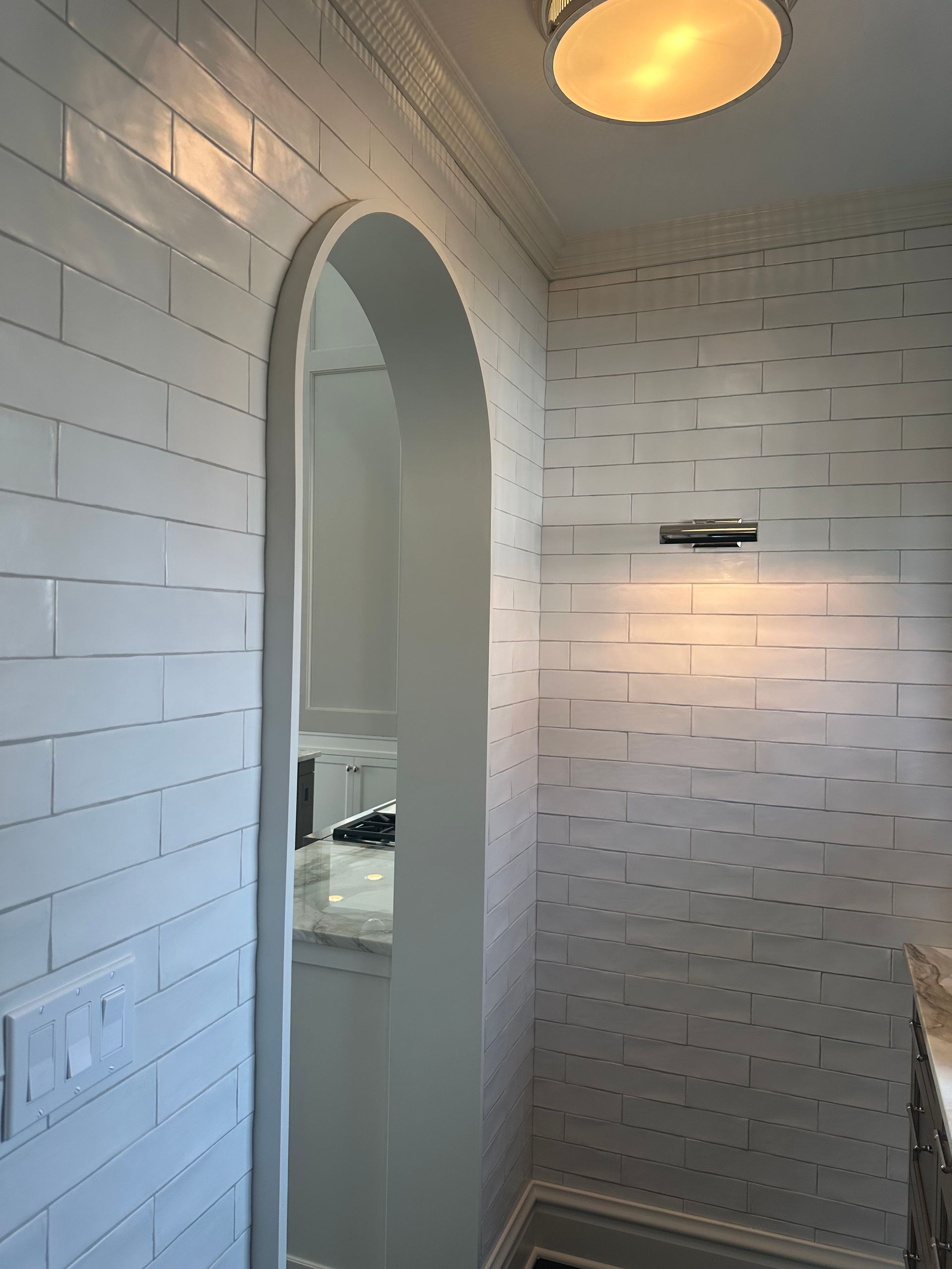 A bathroom with white brick walls and a mirror.