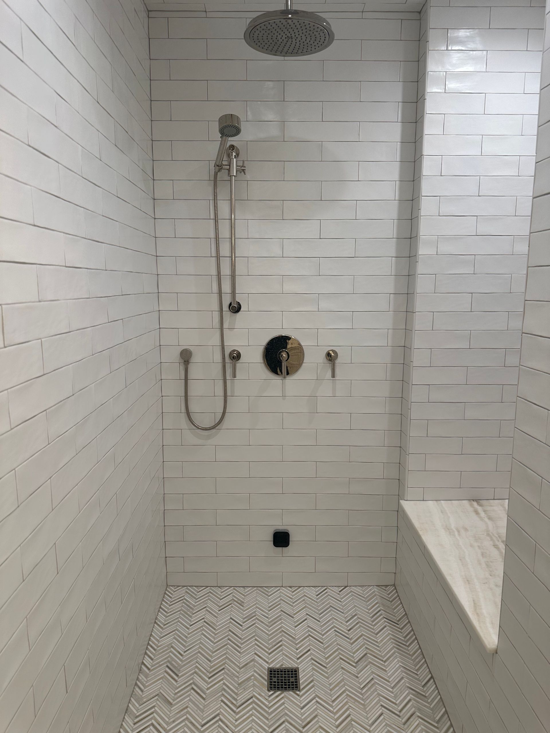 A shower with white tiles and a shower head.