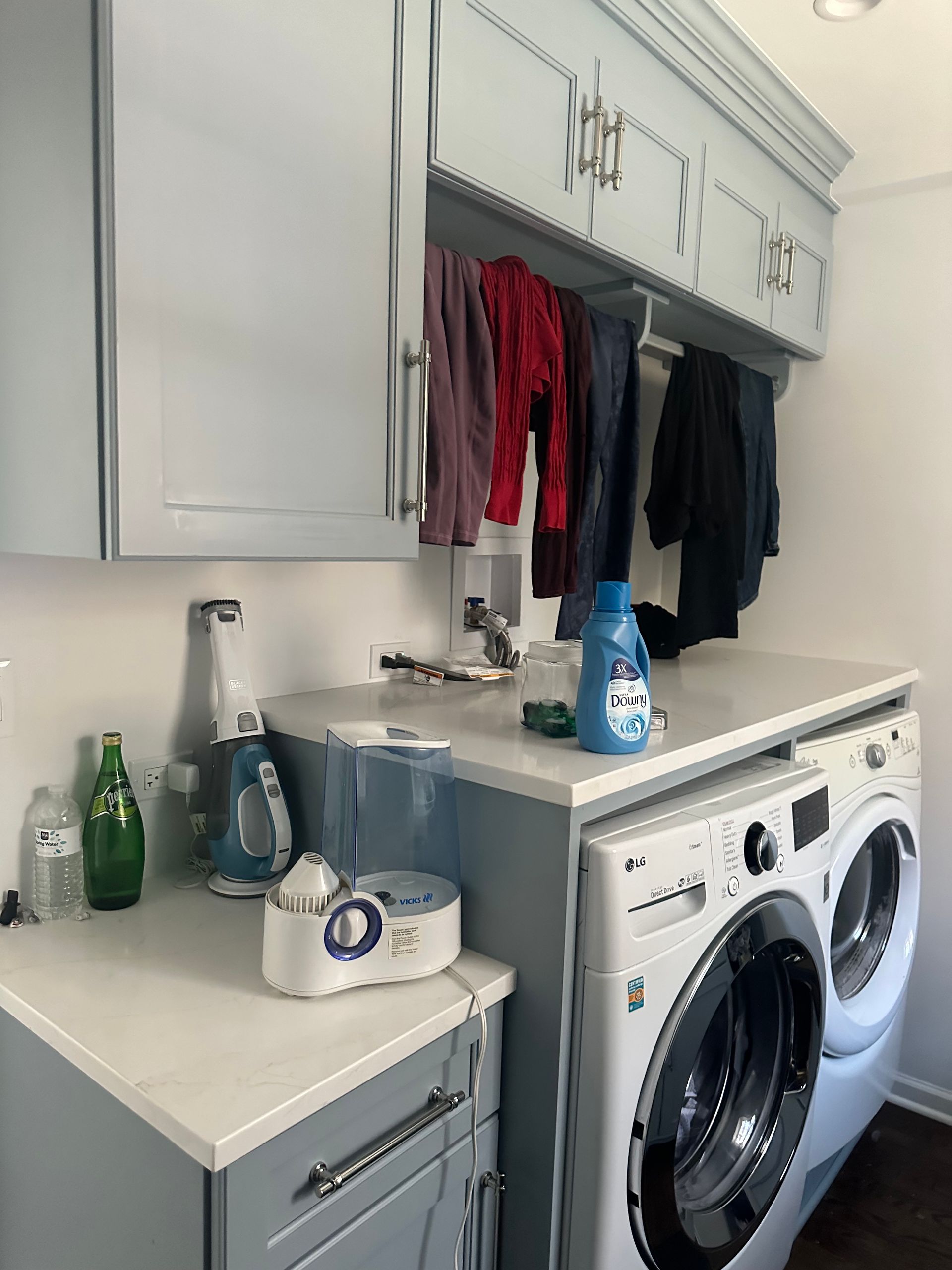 A laundry room with a washer and dryer and clothes hanging on the wall.