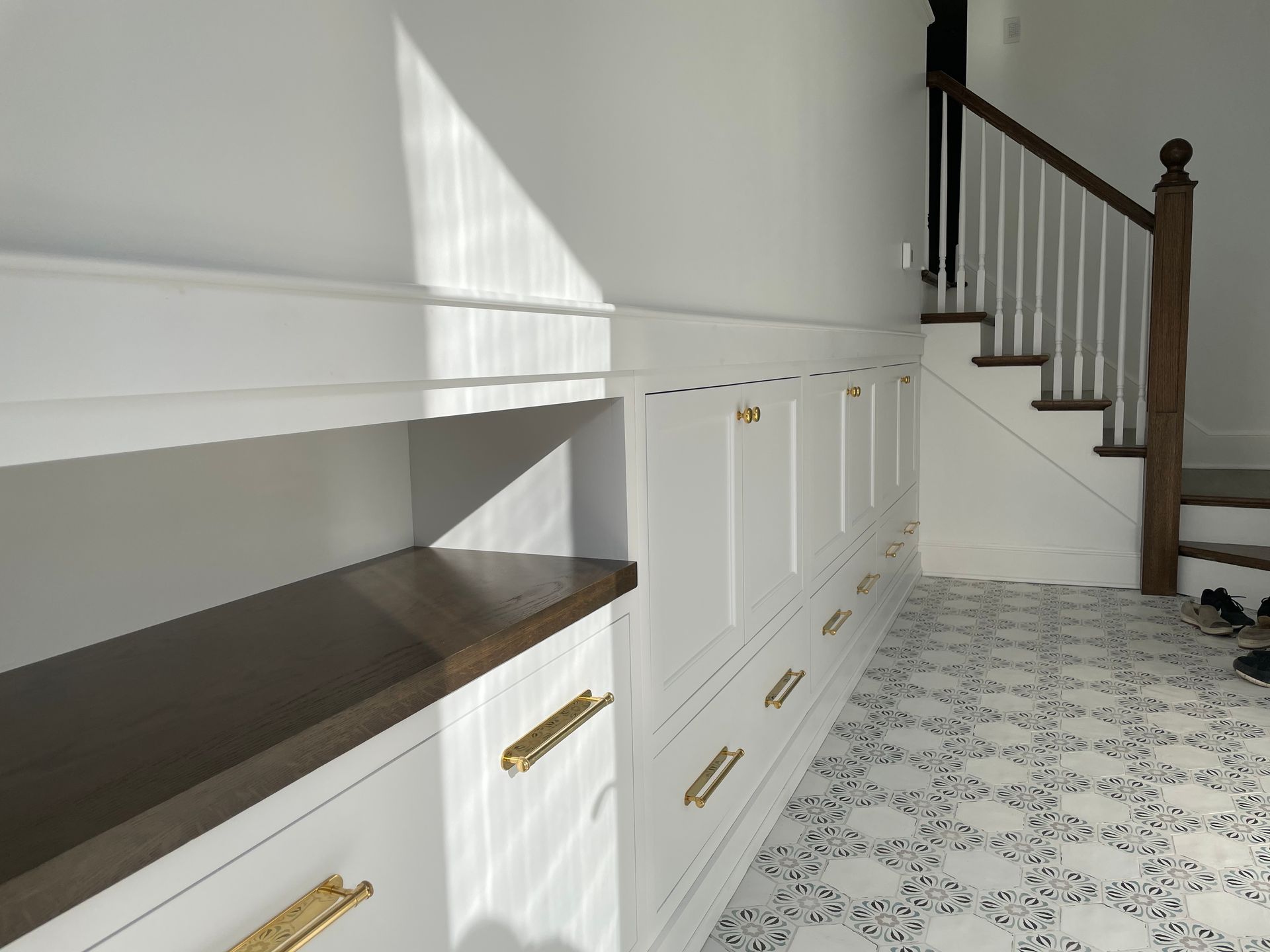A hallway with a staircase and white cabinets