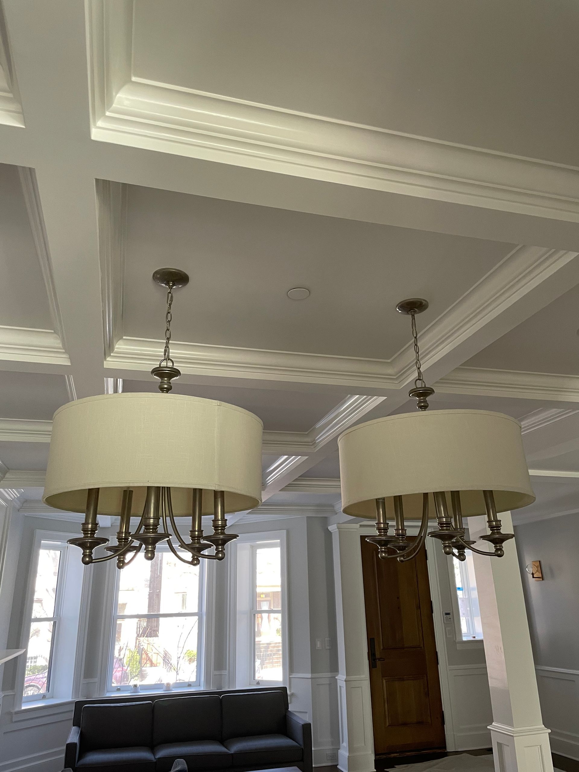 A living room with a couch and two chandeliers hanging from the ceiling.