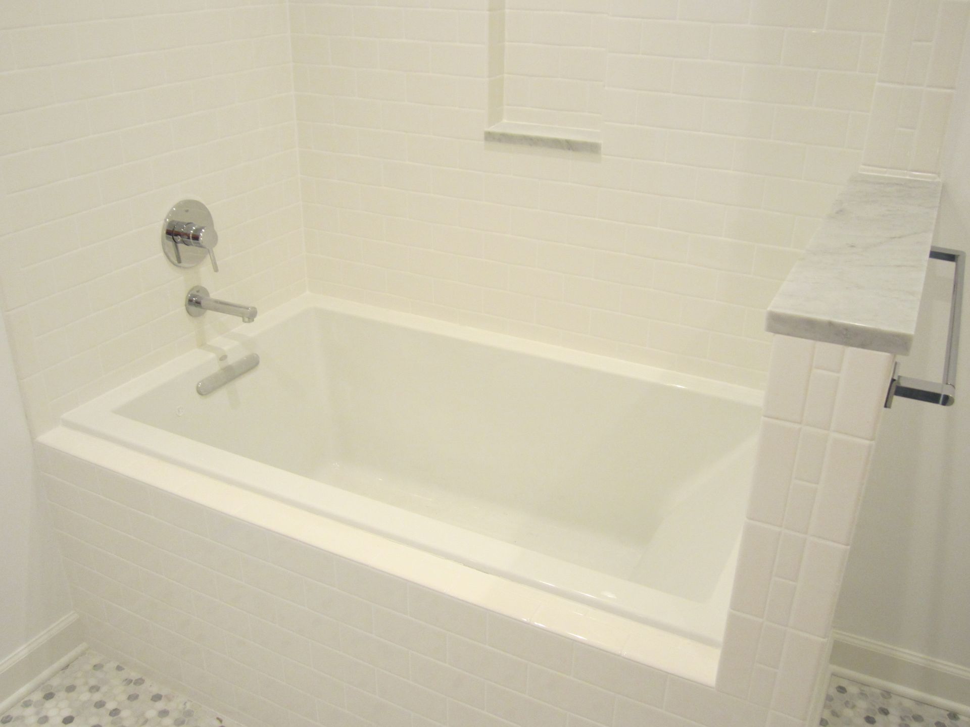 A white bathtub in a bathroom next to a shower.