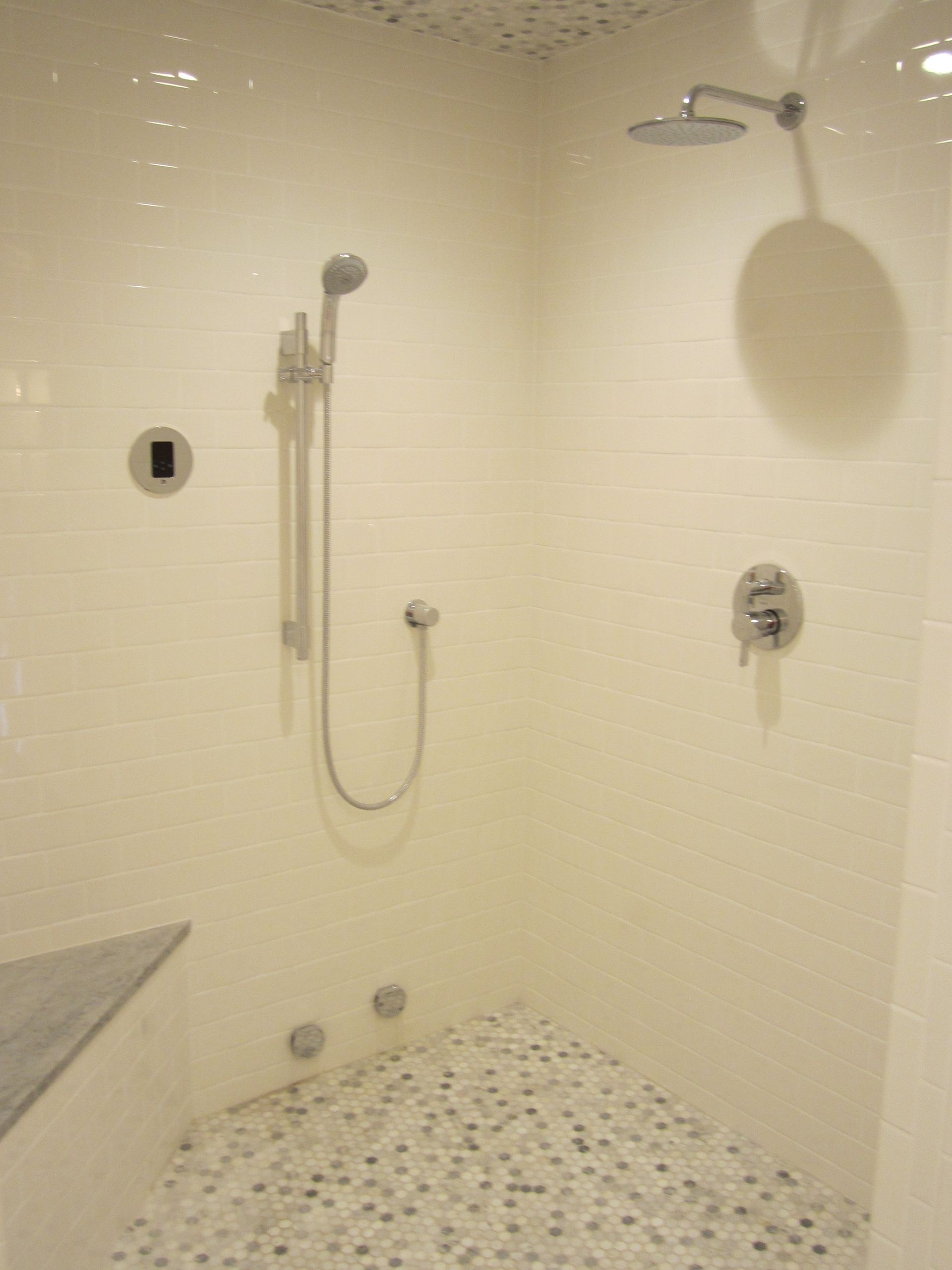 A shower with a shower head and a tiled floor