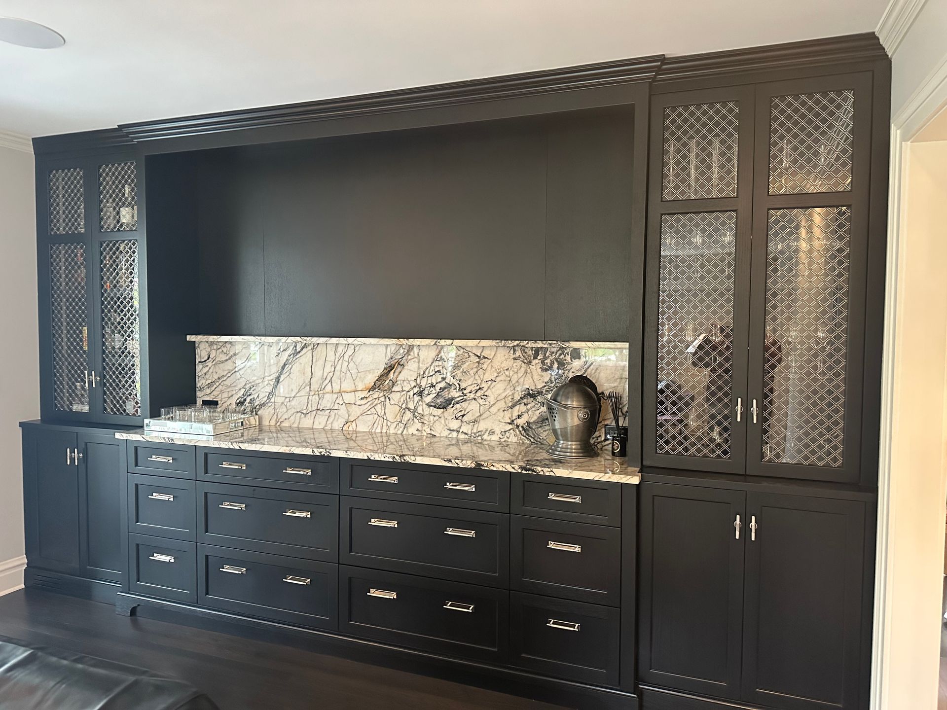 A kitchen with black cabinets and marble counter tops.