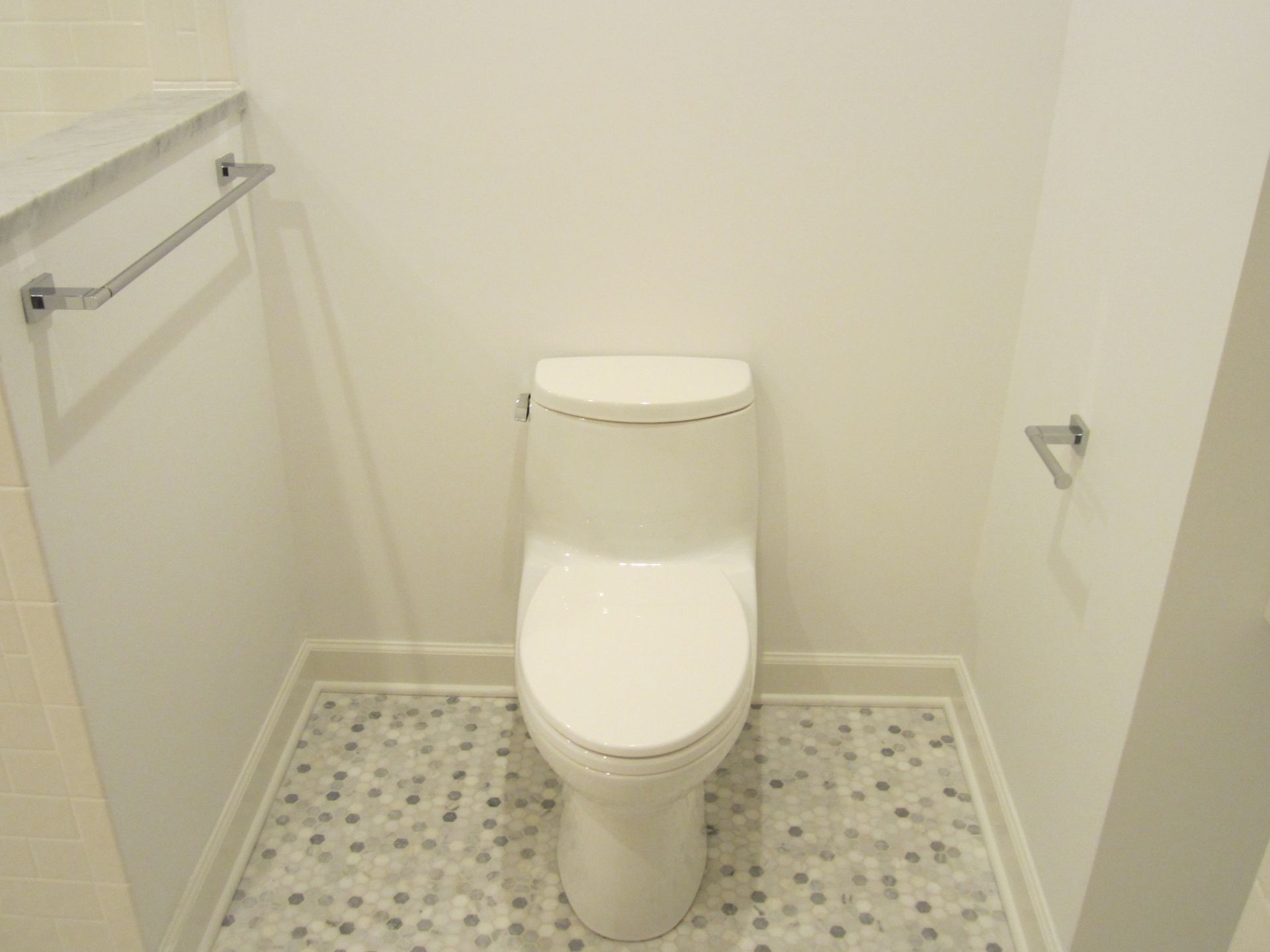 A white toilet is sitting in a bathroom next to a towel rack.