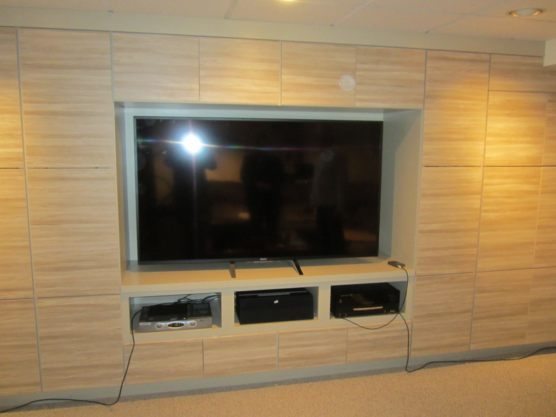 A large flat screen tv is mounted on a wooden wall