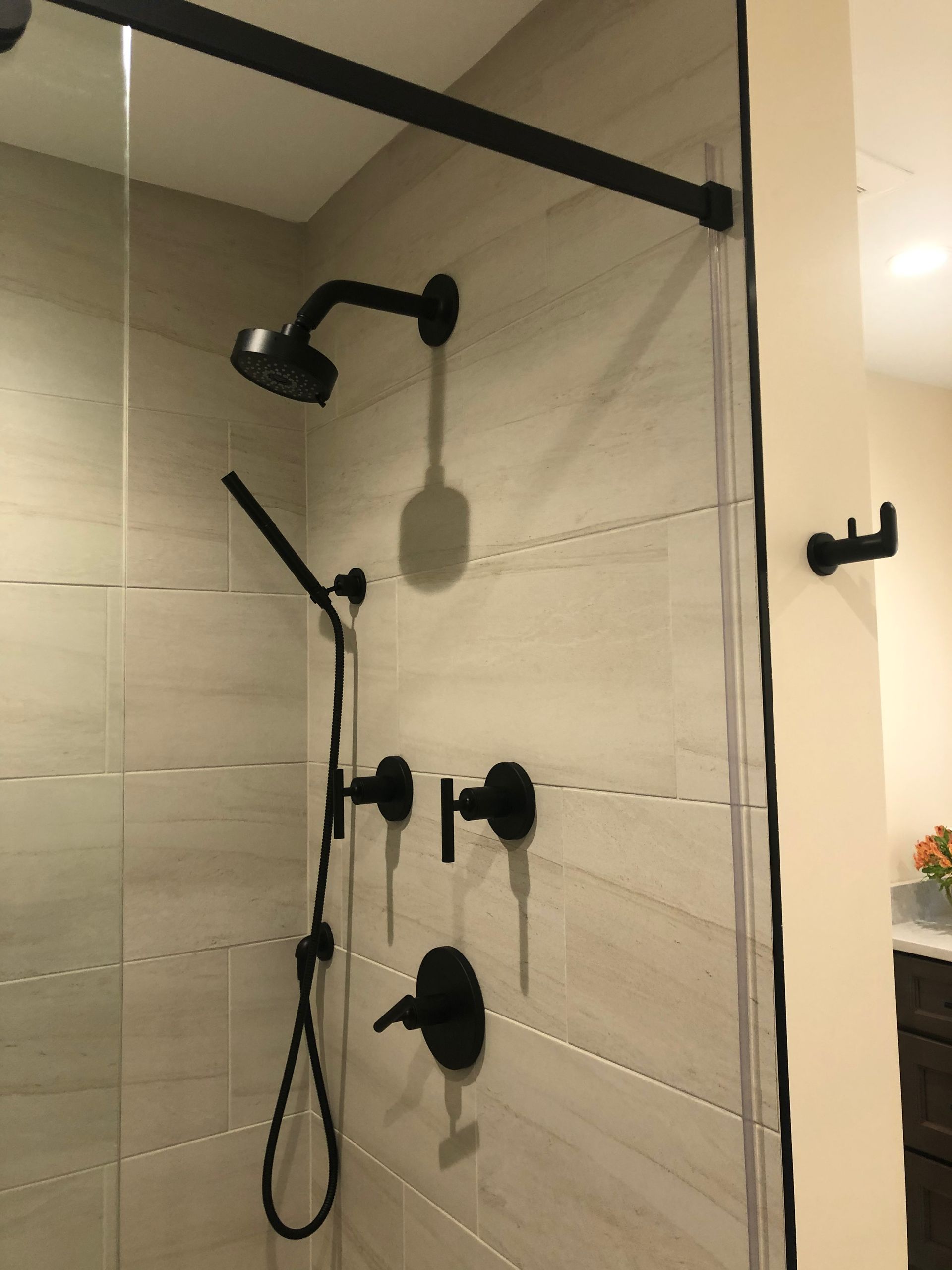 A shower with a black shower head and black faucets