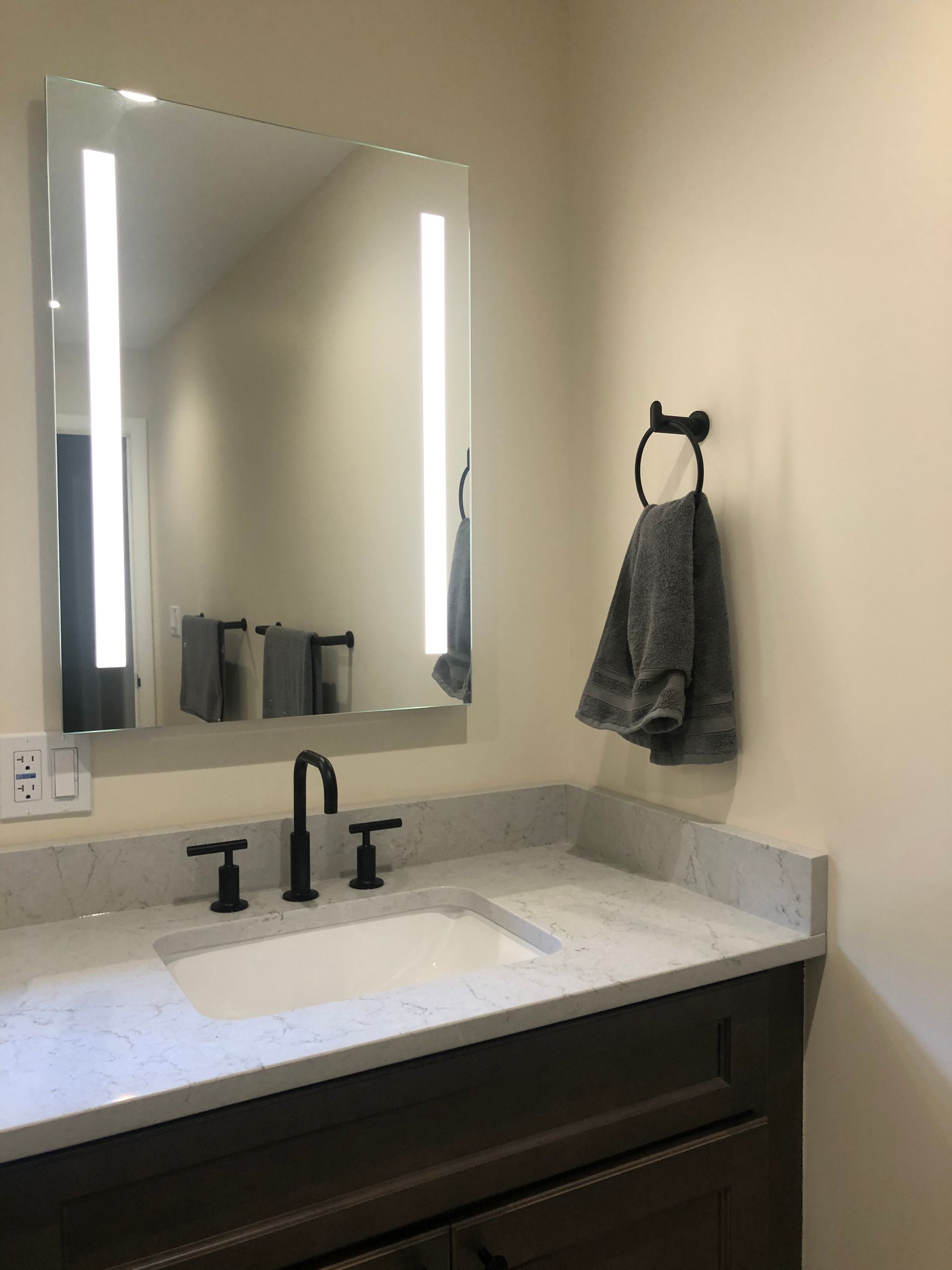 A bathroom with a sink a mirror and a towel hanging on the wall