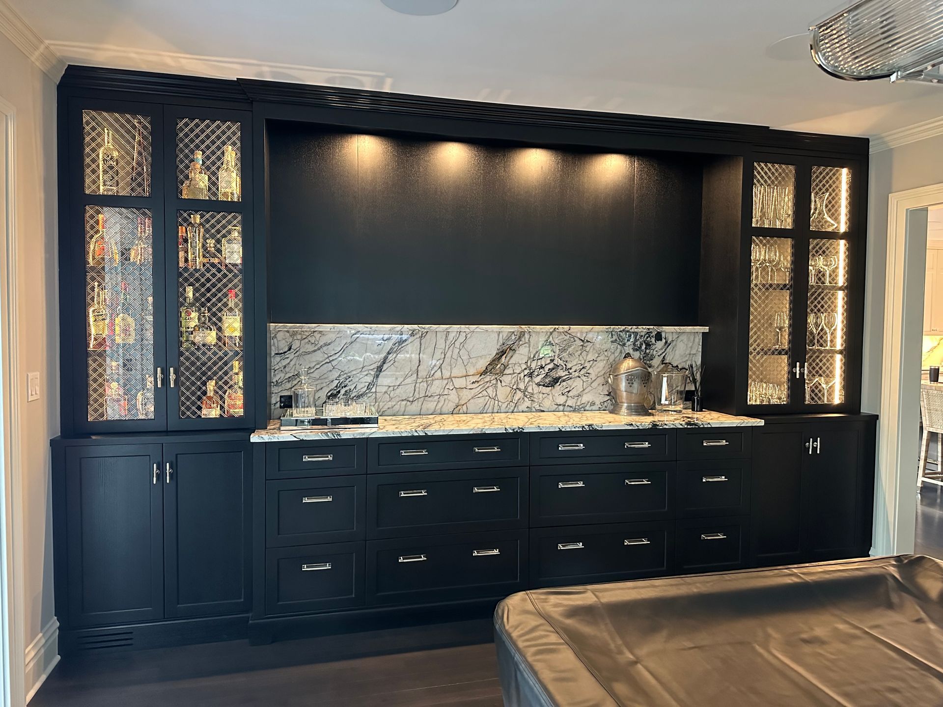A kitchen with black cabinets and a pool table.