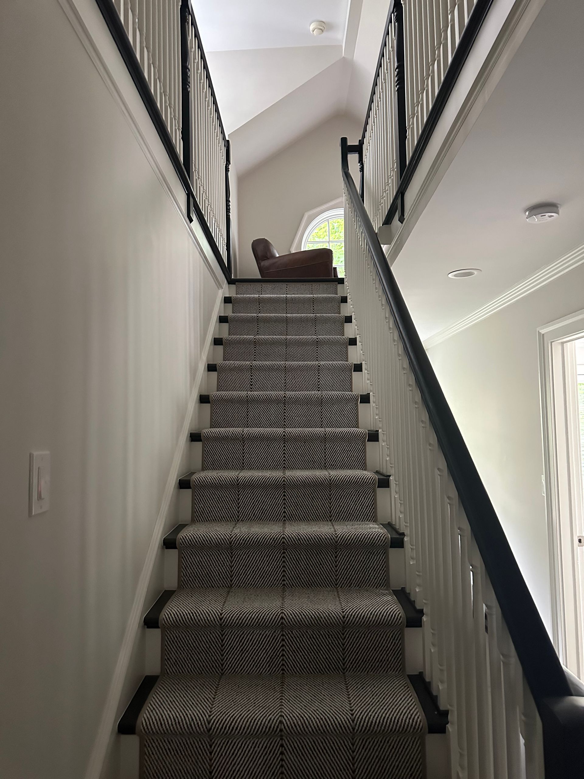 A staircase with a black railing and a zebra print carpet.