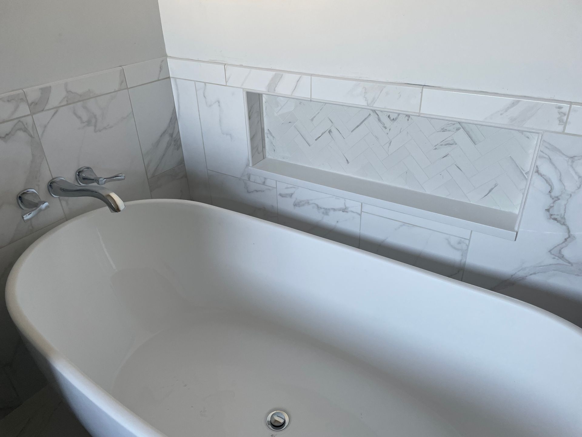 There is a bathtub in the bathroom with a marble wall.
