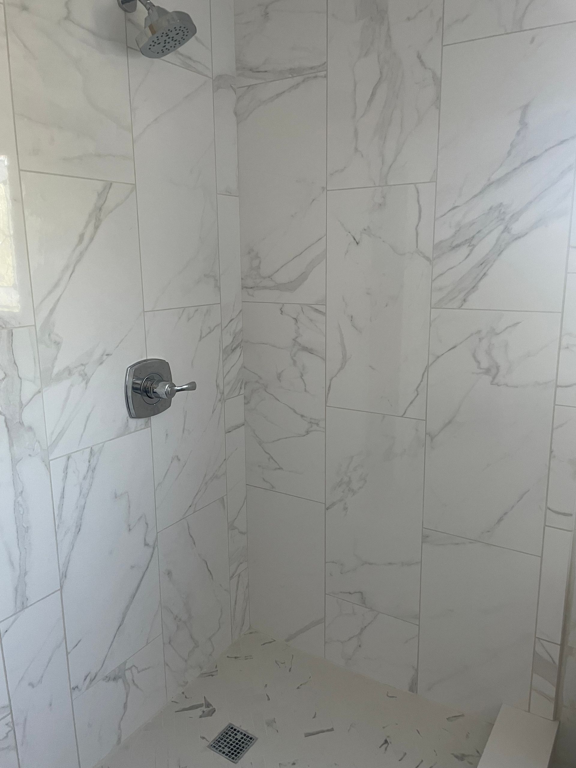 A shower stall with marble tiles and a shower head.