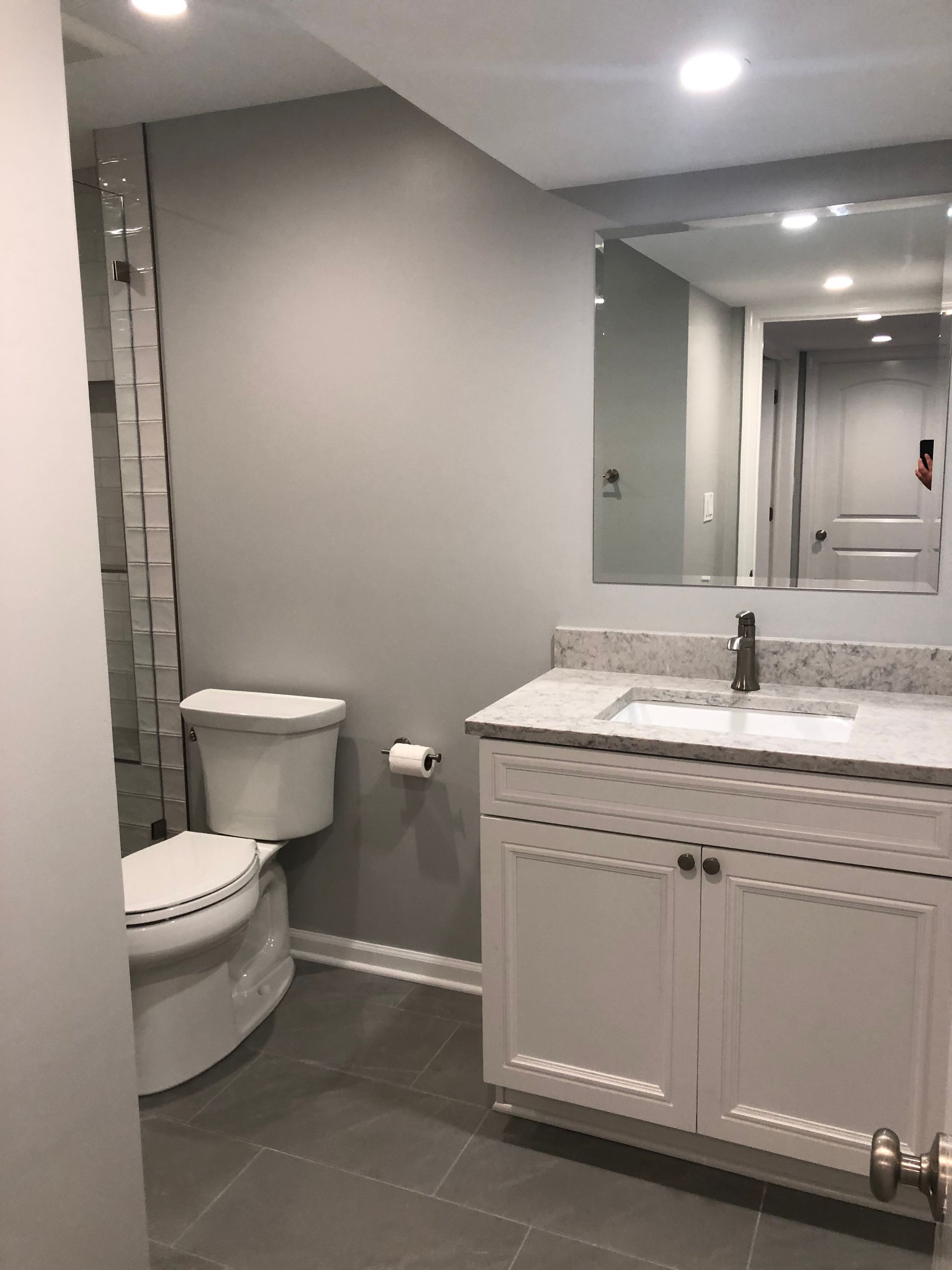 A bathroom with a toilet , sink , and mirror.