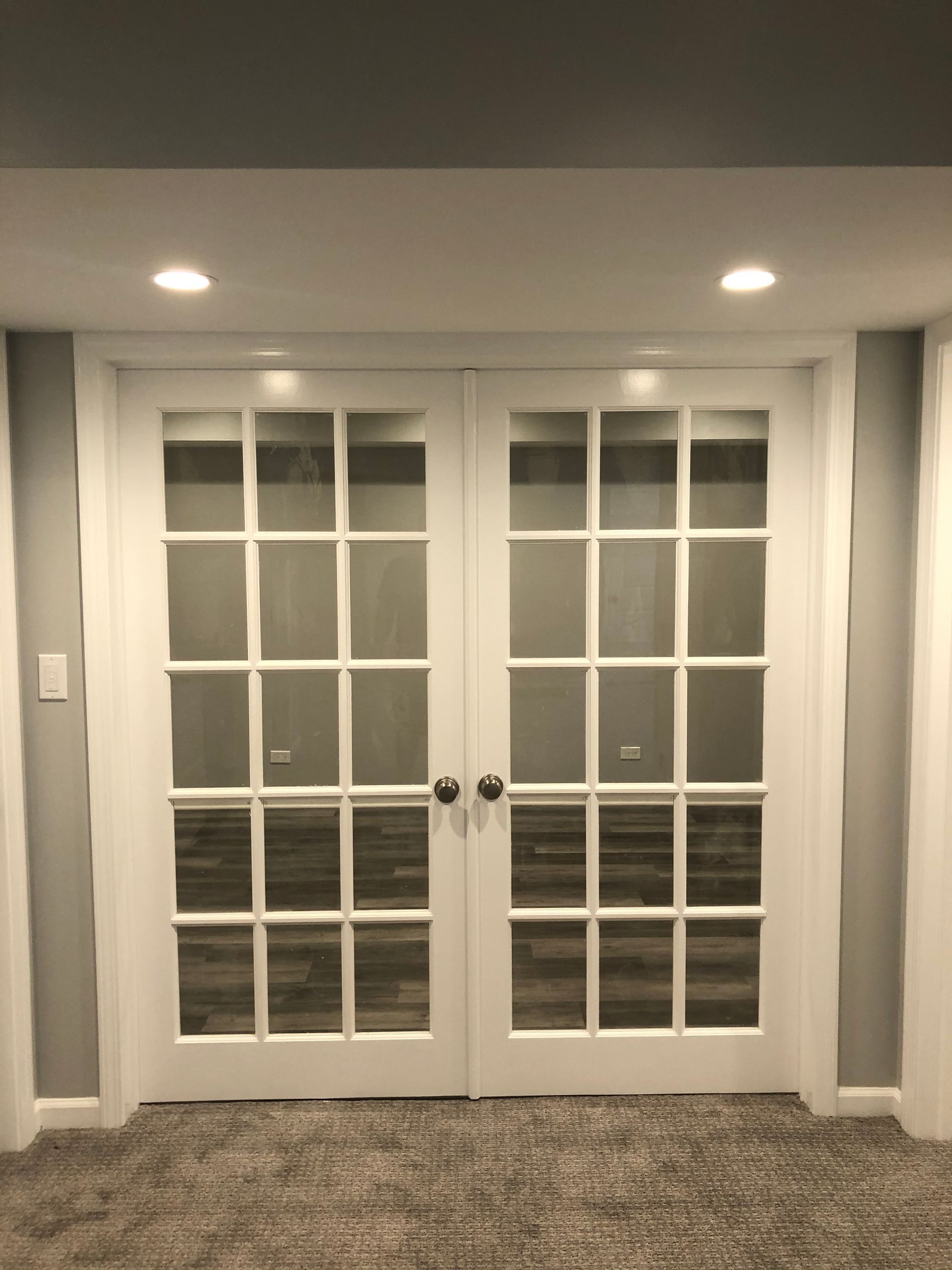 A pair of french doors in a room with a carpeted floor