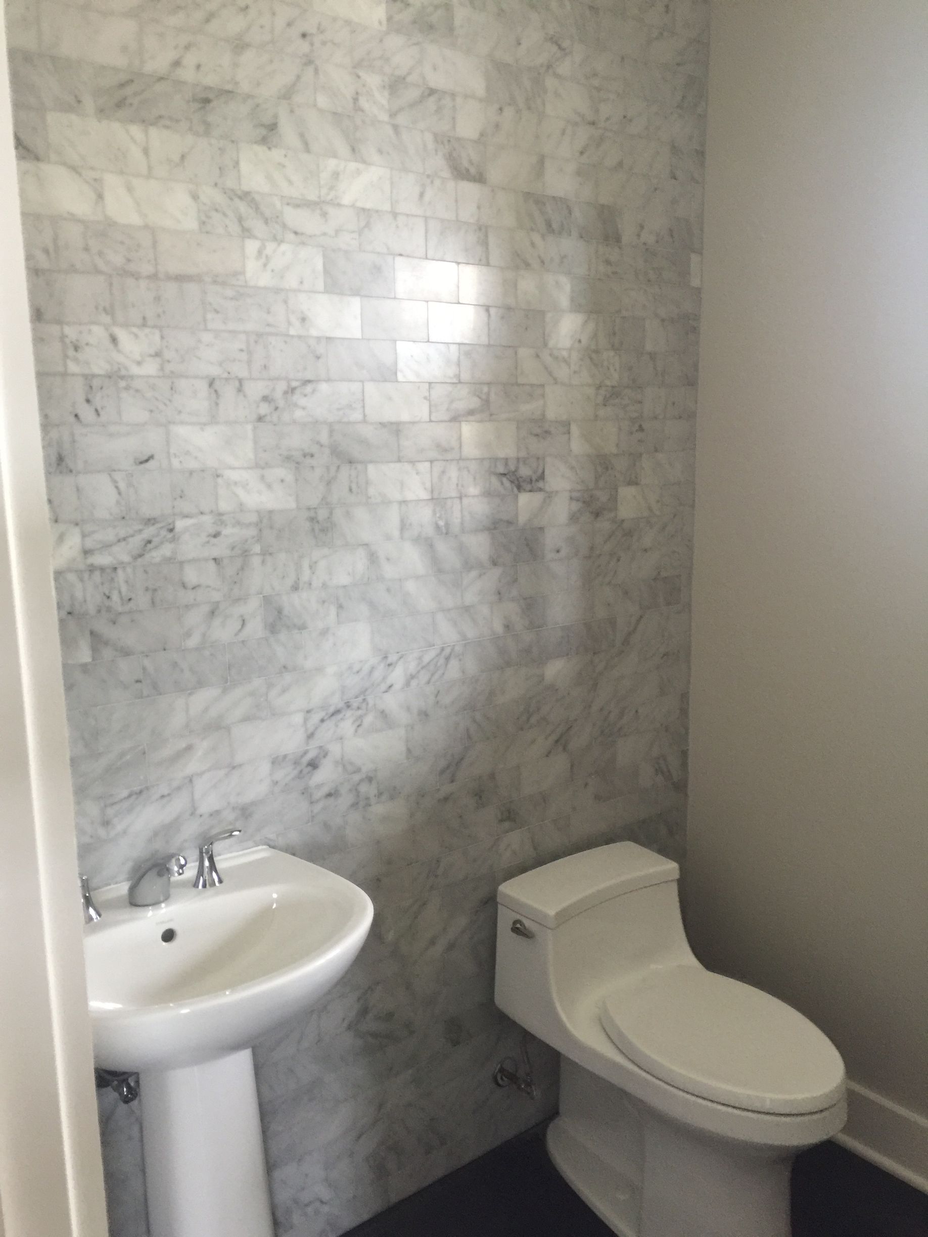 A bathroom with a toilet , sink and marble walls
