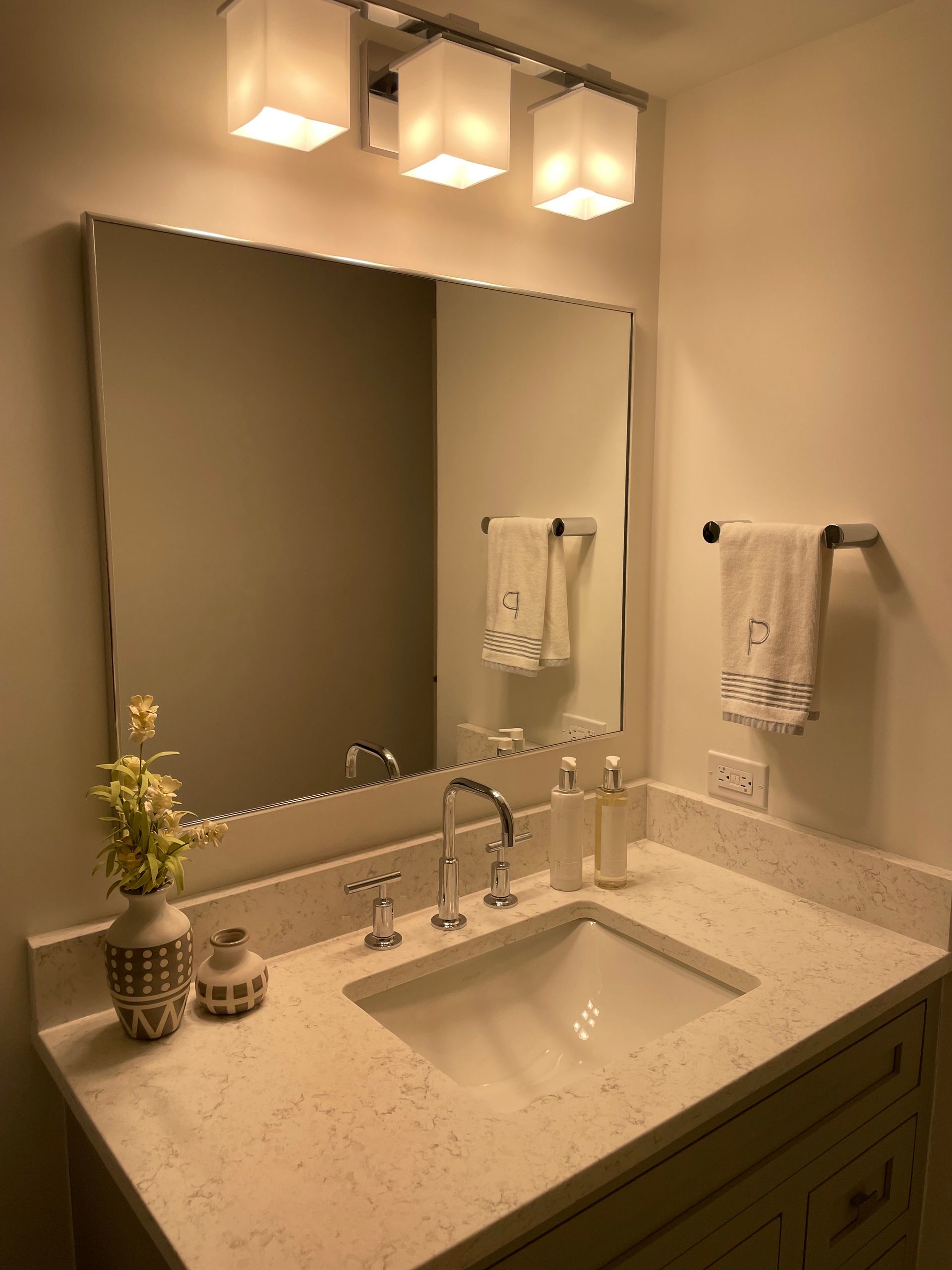 A bathroom with a sink , mirror and towels.