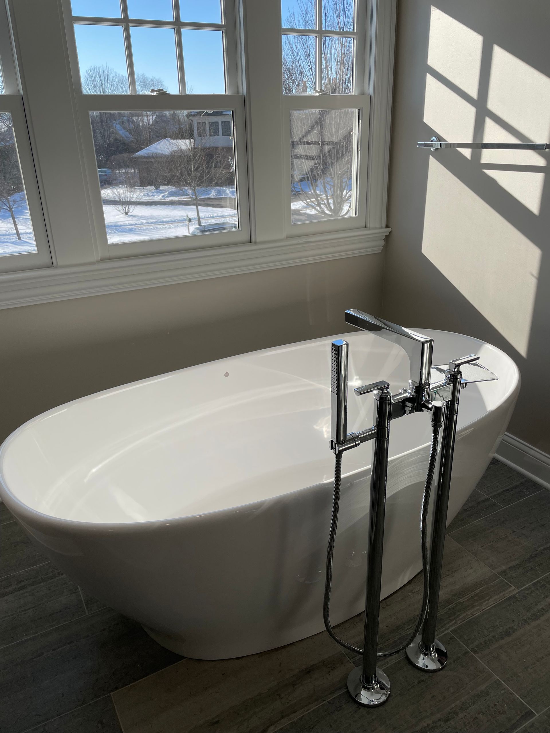 A white bathtub is sitting in a bathroom next to a window.
