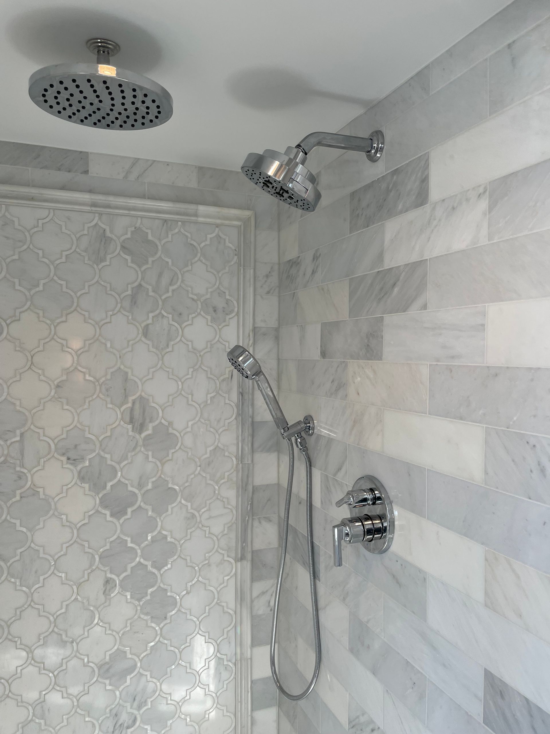 A shower with a round shower head and a handheld shower head.