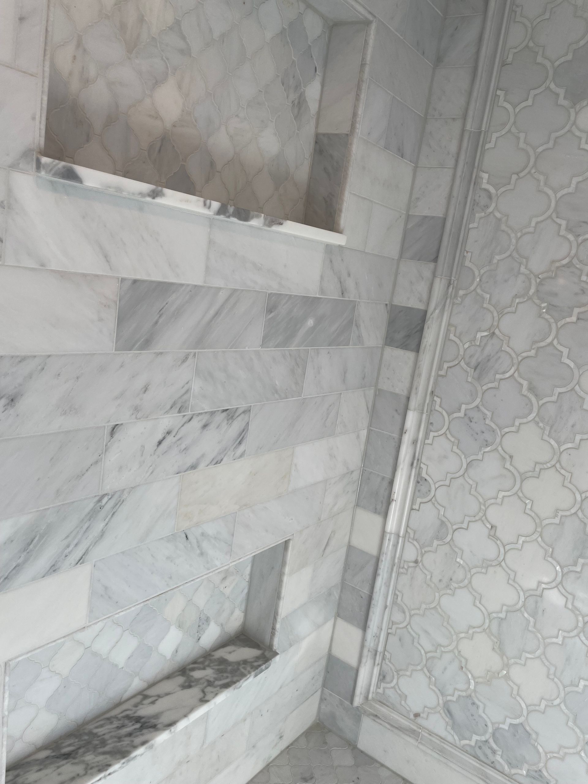 A bathroom with marble tiles and a shower stall.